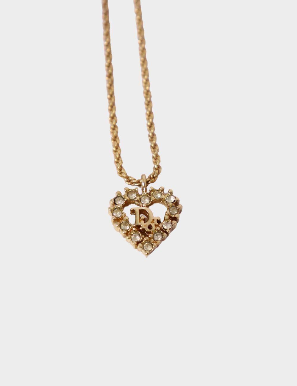 Add a romantic vintage touch to your jewelry collection with this Christian Dior heart pendant necklace. Crafted in gold-tone metal, it features a sparkling crystal-encrusted open heart design with the iconic Dior logo at the center. Hanging from a