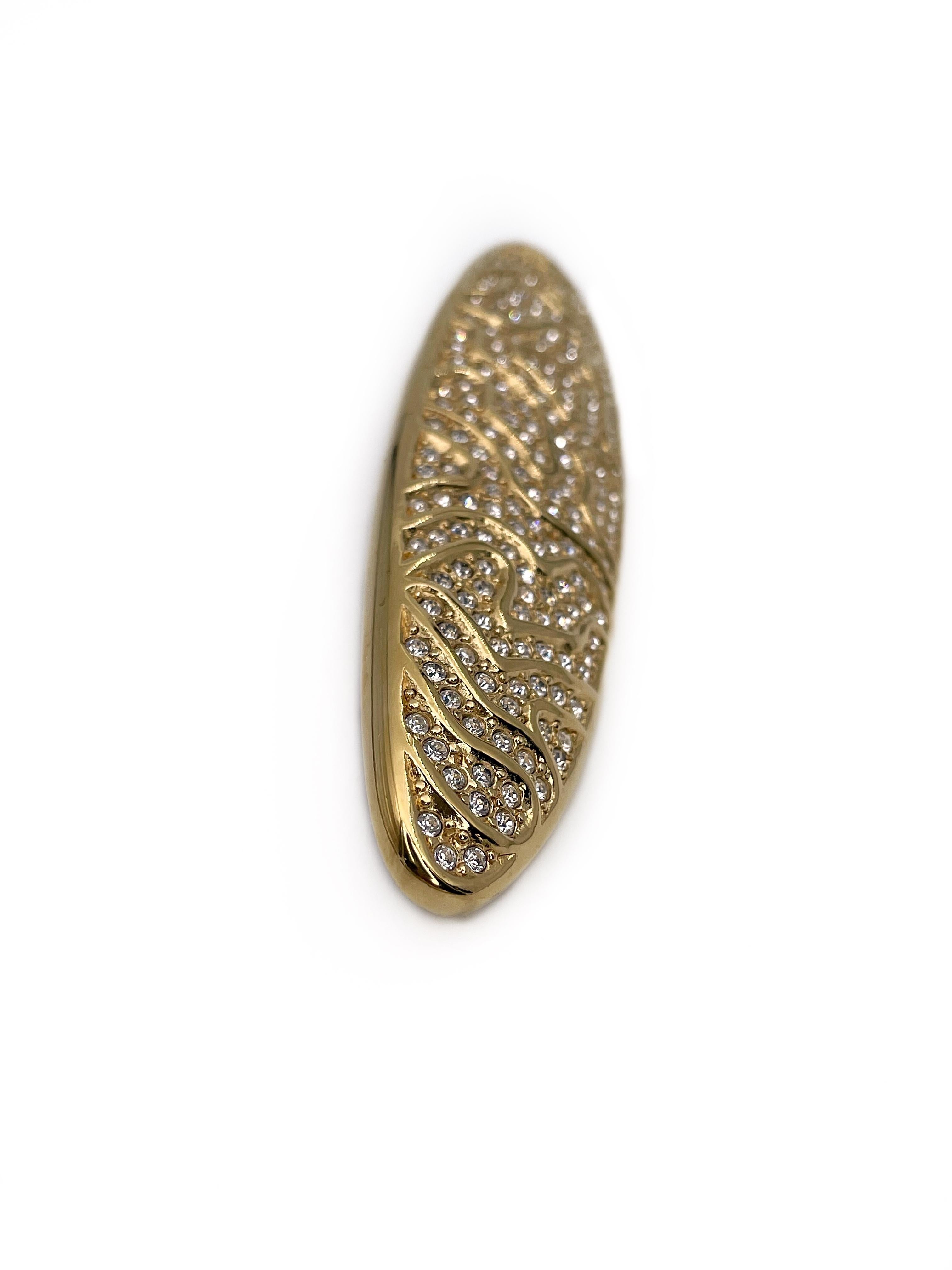This is a yellow gold tone horizontal oval brooch designed by Christian Dior in 1990’s. This piece is gold plated, adorned with clear rhinestones. 

It beautifully pairs wit the same design clip on earrings available in our account.

Markings: