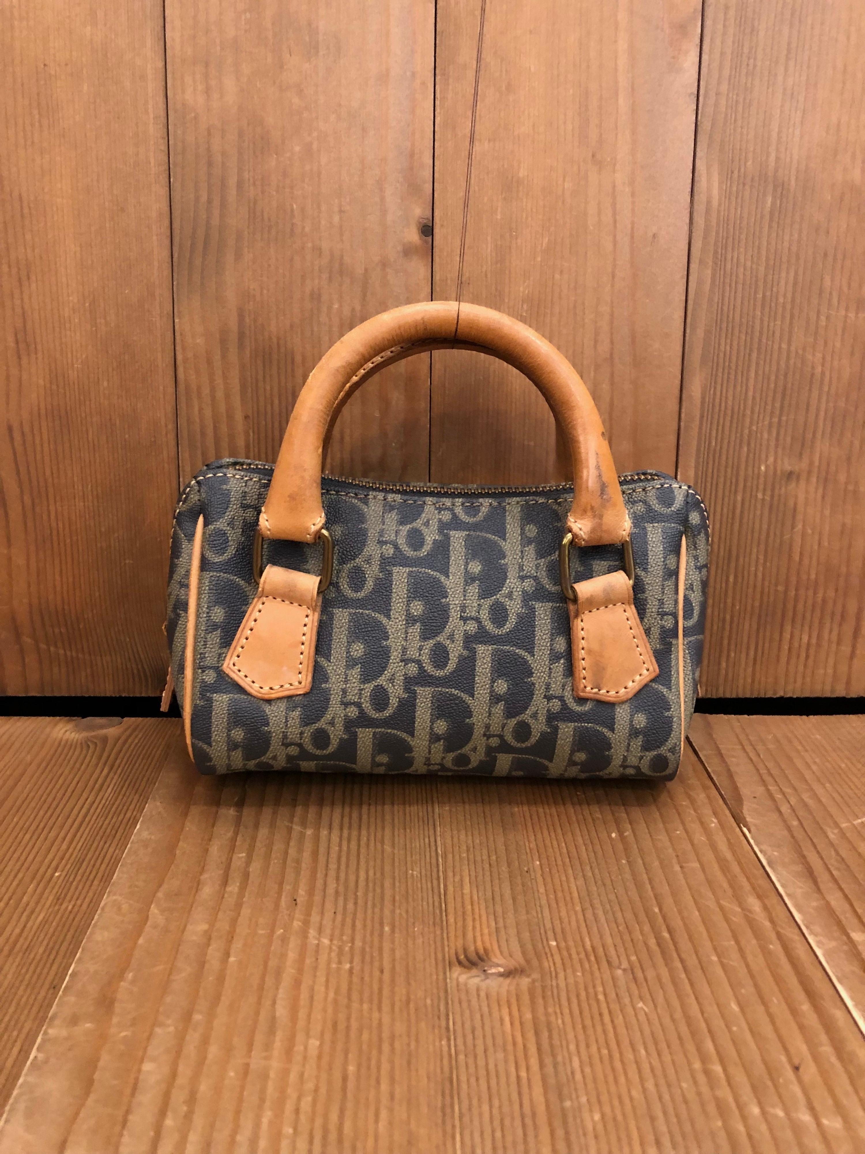 This vintage Christian Dior mini boston bag is crafted of coated trotter canvas in grey/khaki. Top zipper closure opens to a canvas interior. Made in France. Measures approximately 6 x 4 x 3 inches Handle Drop 2 inches. Comes with third party strap.
