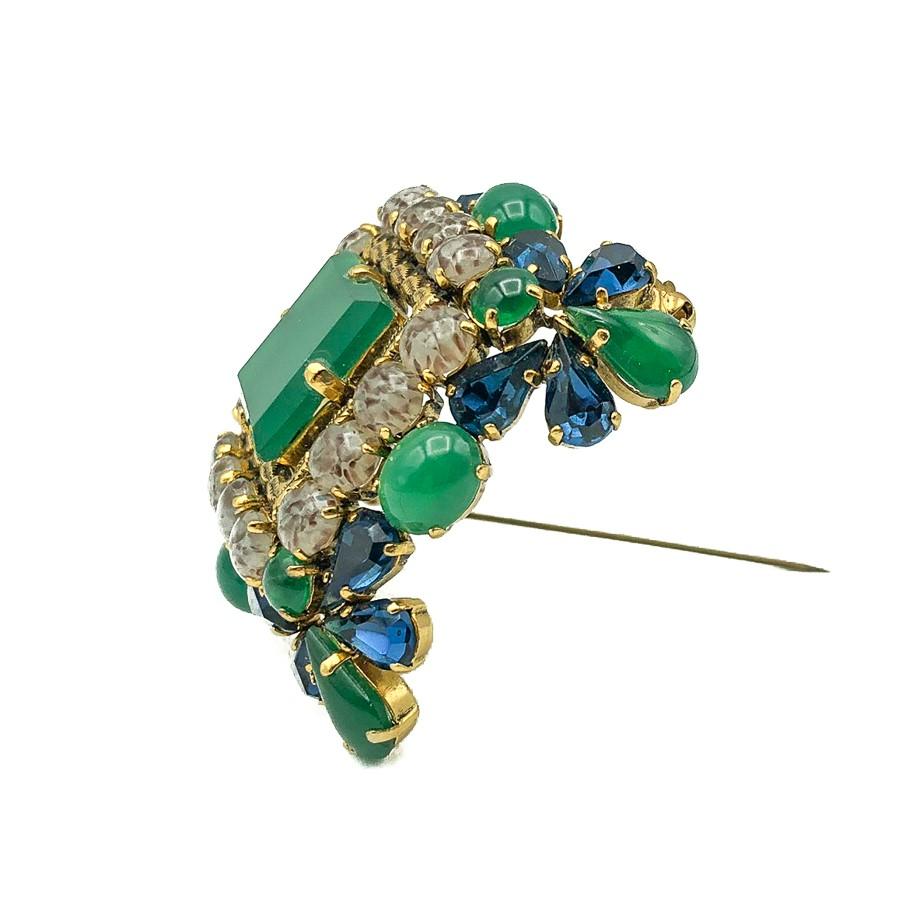 A stunning Vintage Dior Jade Brooch with an outstanding design in three dimensions. Crafted from the most exquisite array of fancy cut glass stones cleverly emulating sapphires, jade and agates and set in gold plated metal. Each stone is claw set.