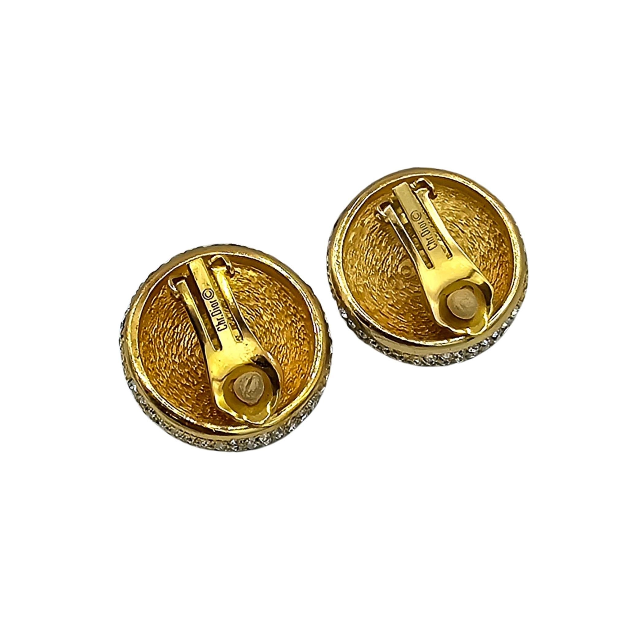 This is a beautiful and authentic pair of Christian Dior Earrings. It has a large faux mabe pearl as centrepiece and has a gold, twisted rope border surrounded further by two rows of sparkling white gems.  No piercing? No problem as this comes in a