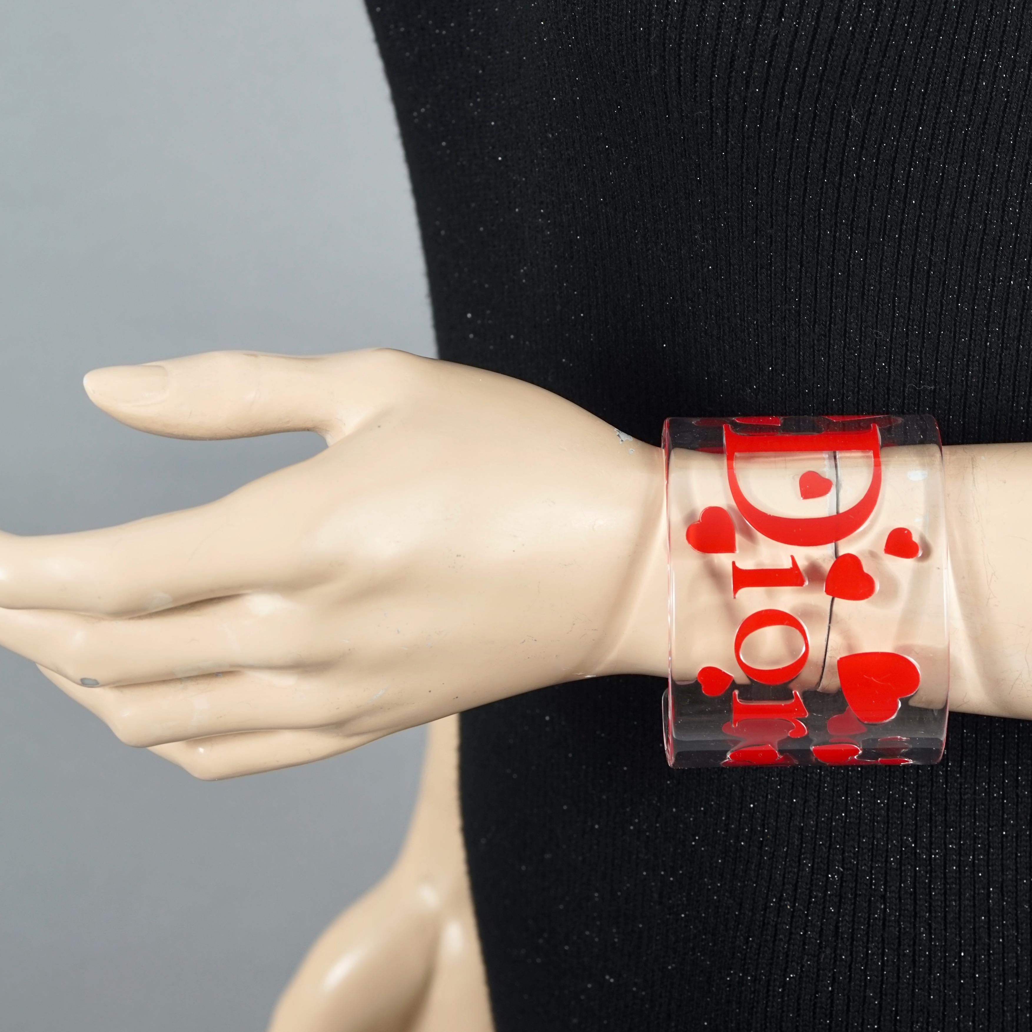 Vintage CHRISTIAN DIOR Logo Heart Lucite Cuff Bracelet

Measurements:
Height: 2.24 inches (5.7 cm)
Inner Diameter: 7.08 inches (18 cm)

Features:
- 100% Authentic CHRISTIAN DIOR.
- Clear lucite acrylic cuff with red DIOR logo and hearts.
- Pieces in