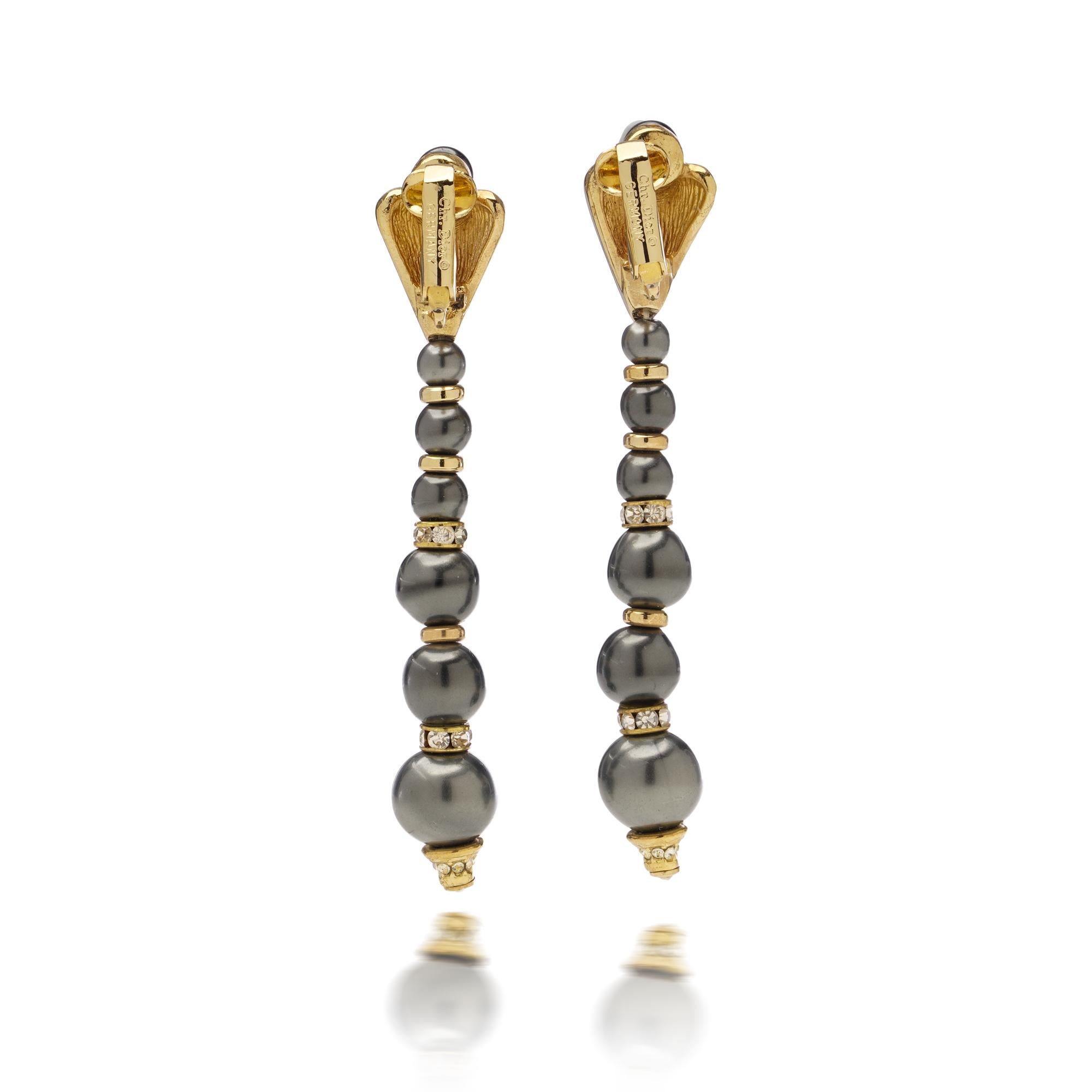 These striking vintage Dior dangle earrings combine timeless glamour with bold design. Crafted with graduated grey beads and sparkling crystal accents set in a gold-tone frame, the earrings feature an elegant clip-on fastening for comfort and style.