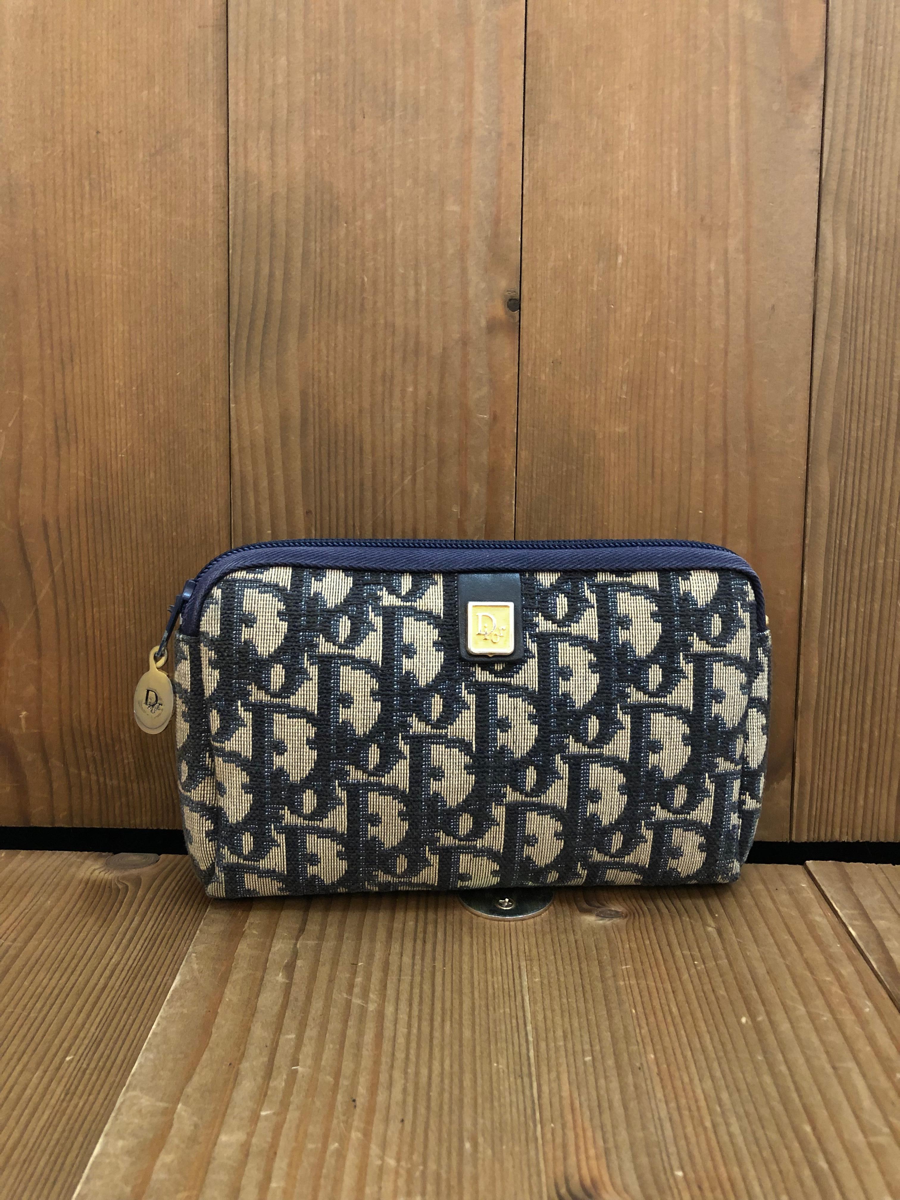 This Vintage CHRISTIAN DIOR mini vanity pouch is crafted of Dior signature Trotter jacquard in navy featuring gold toned hardware. Top zipper closure opens to a coated interior in navy. Made in France. Measures approximately 6.25 x 4 x 1.5 inches.