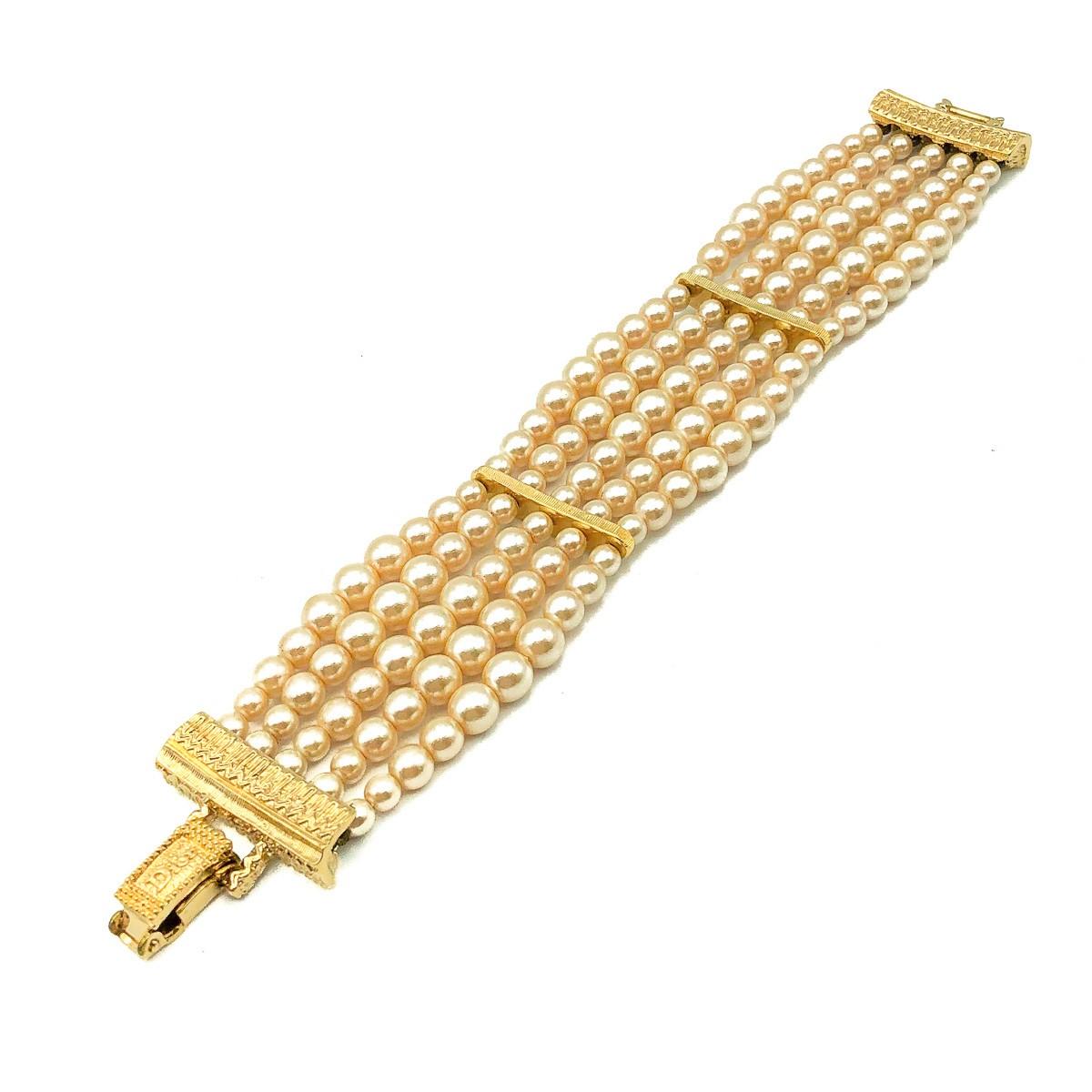 A truly stunning Vintage Dior Pearl Bracelet. Crafted in gold plated metal with graduated glass simulated pearls; attention to detail as always with Dior. Five rows of gorgeous creamy pearls are sectioned with gold plated bars to create a structured
