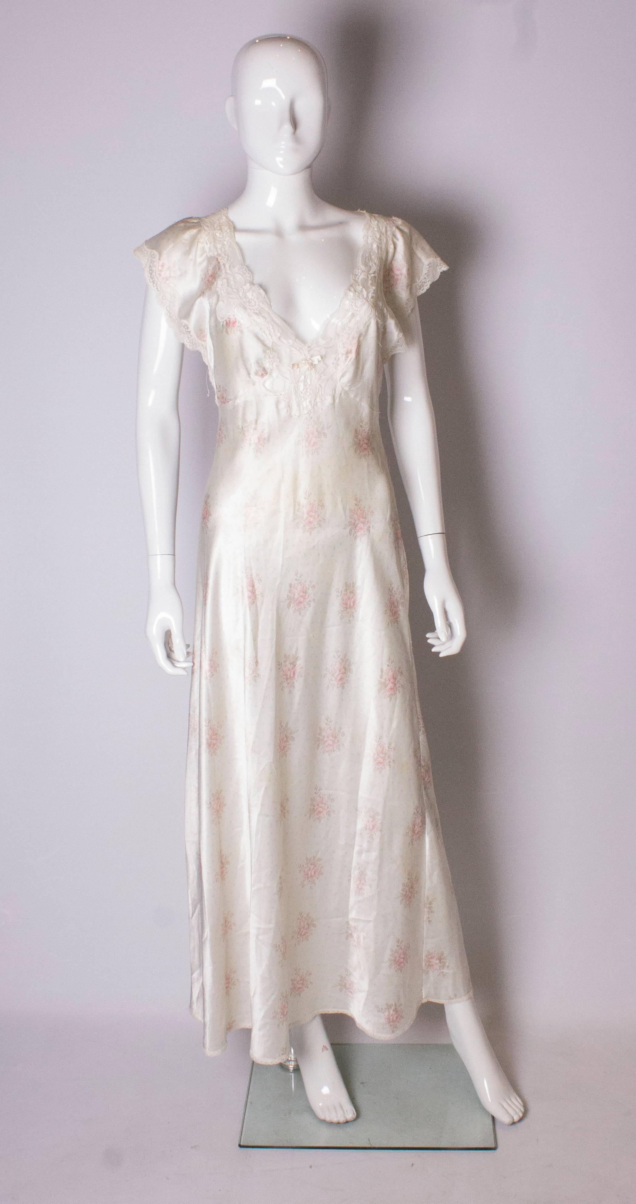 A pretty nightdress by Christian Dior. The fabric is a silky satin with an ivory background with blue dots and a rose print. it has a v neckline with lace trim ,and ;ace on the hem and cuffs.