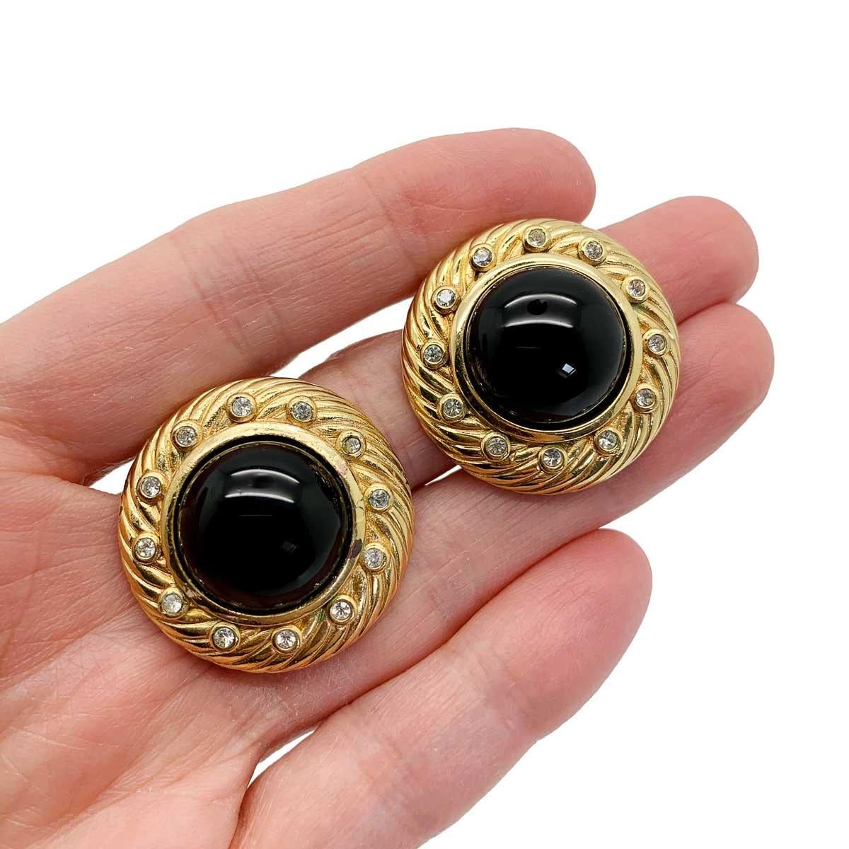A super stylish pair of vintage Dior onyx glass earrings. Featuring a large onyx glass cabochon stone framed by a deep ribbed gold mount finished with white chatons.
With archive pieces from her own Dior collection displayed in London's highly