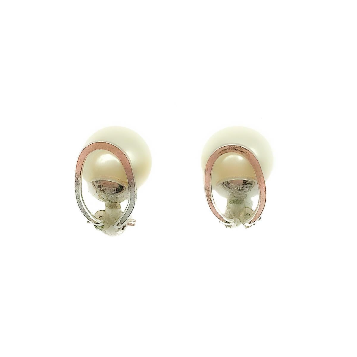A delightfully feminine pair of Vintage Dior Petite Pearl Earrings. Crafted in rhodium plated metal with a full glass faux pearl sitting in a cup shaped mount with a french style hoop clip mechanism. Signed, in very good vintage condition, approx.