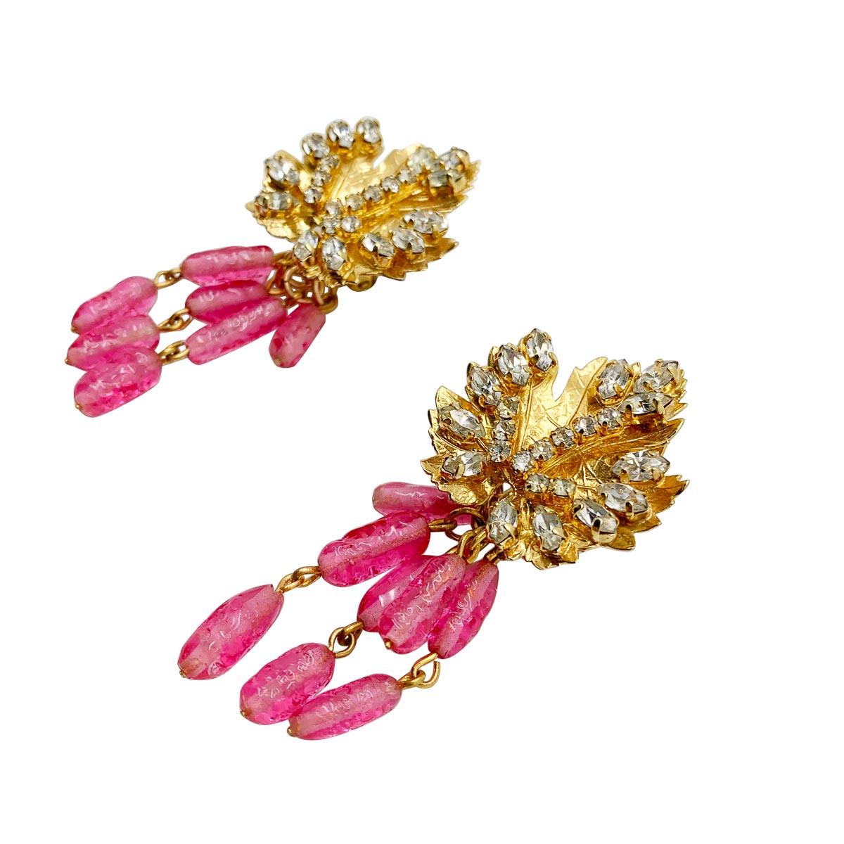 Ein außergewöhnliches Paar Vintage-Ohrringe von Dior aus den 1970er Jahren. Das Blattmotiv auf der Spitze ist mit weißen Chaton-Kristallen besetzt, die von rosafarbenen Kunstglasperlen abgelöst werden, die für einen edlen Look sorgen.
Mit
