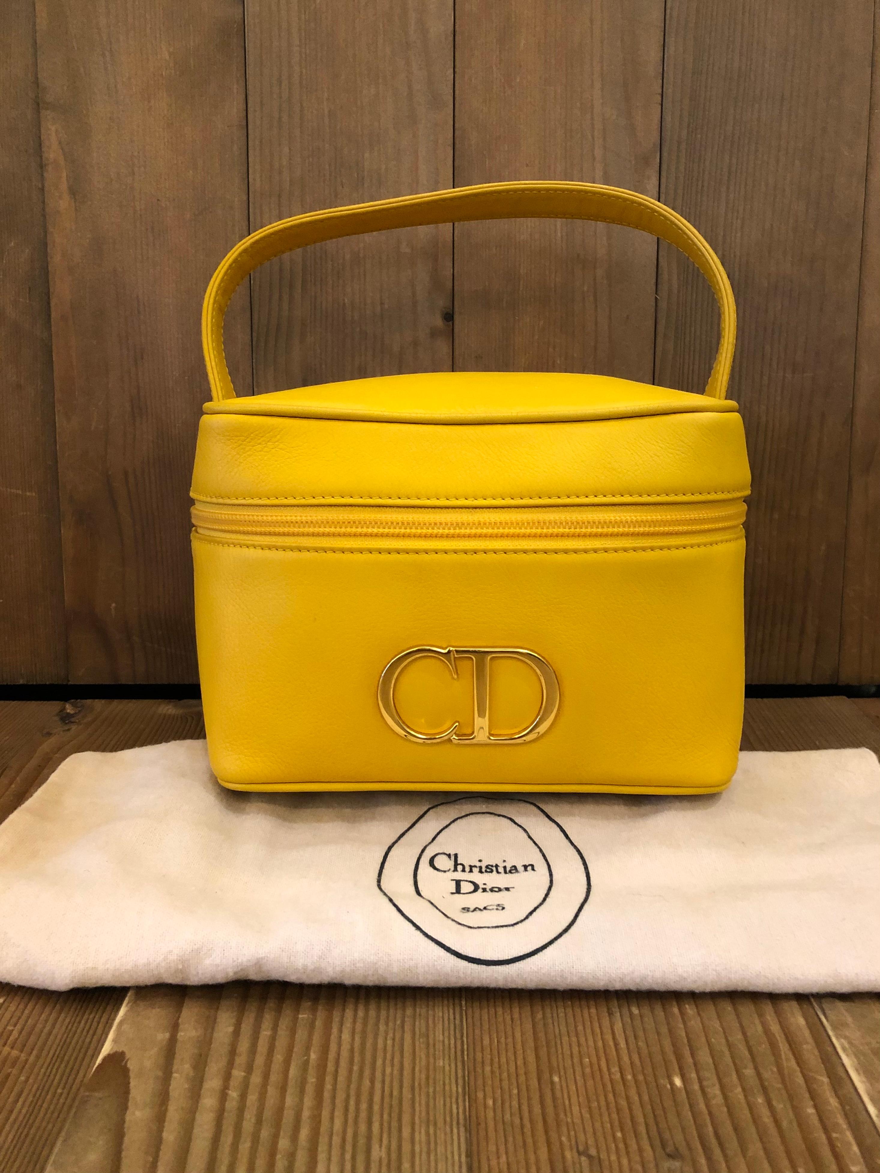 This vintage CHRISTIAN DIOR vanity case handbag is crafted of vivid yellow leather adorned with an oversized gold toned CD logo. Zip around closure which opens to a black leather interior. Perfect for cosmetic storage or carrying as a handbag to