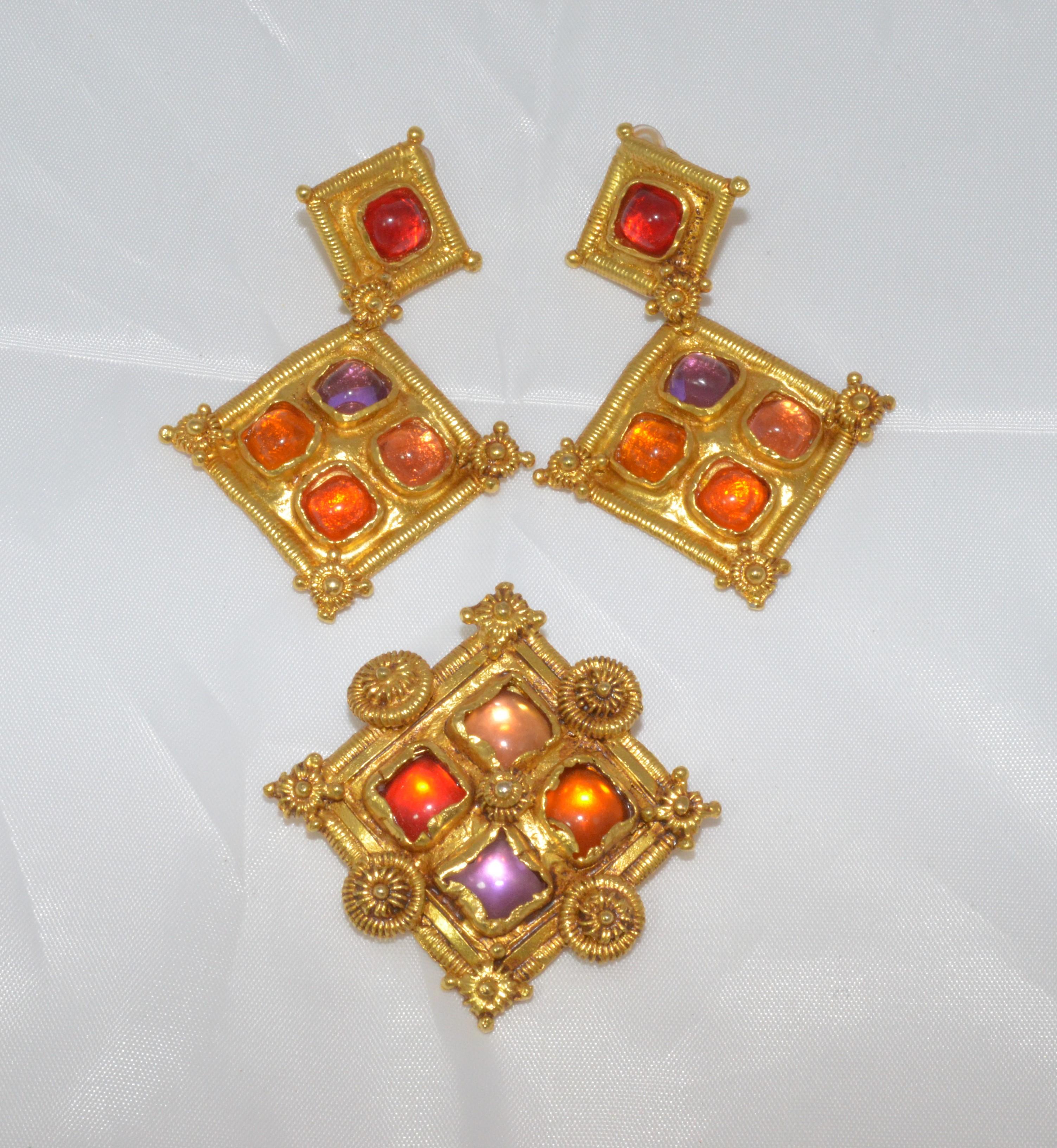 Christian Lacroix Brooch and Clip-On Earrings Set -- Set is featured in gold with red, purple, and orange stones (possibly glass) and designer stamp at the backs. Brooch and earrings are in excellent pre-owned condition.

Measurements:
Earrings -