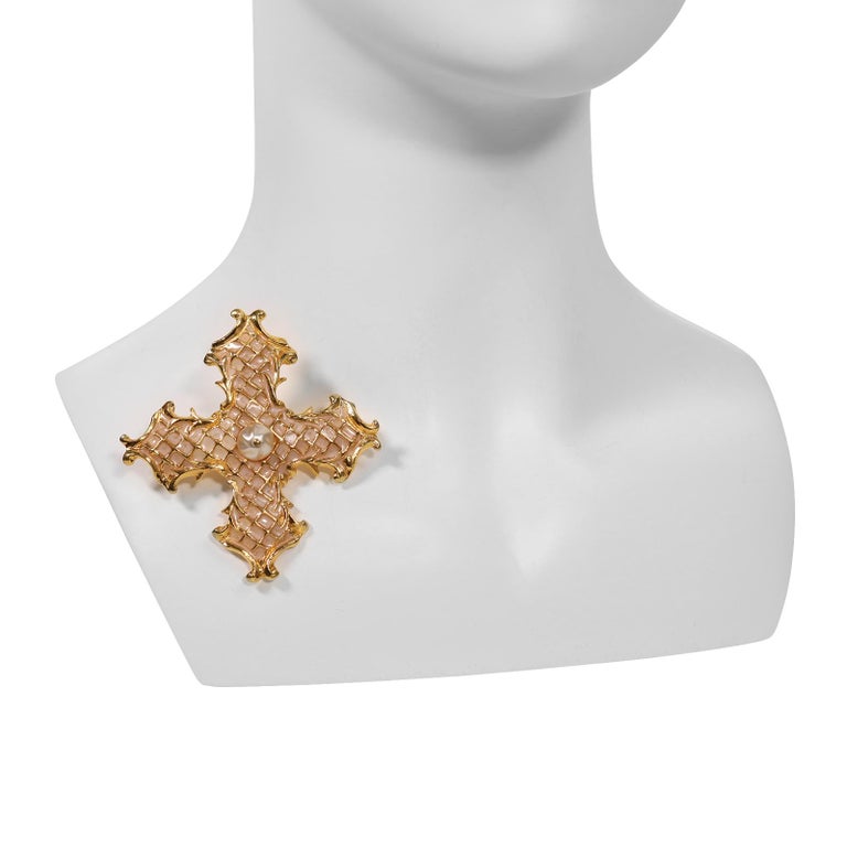 Vintage Christian Lacroix Enamel and Faux Pearl Cross. Gold Tone with Pink under the Gold.  Pearl Sits in the middle. Could be worn on a Link Necklace. 

Lacroix says his fashion icon is The Queen of England. One of the reasons for that is her