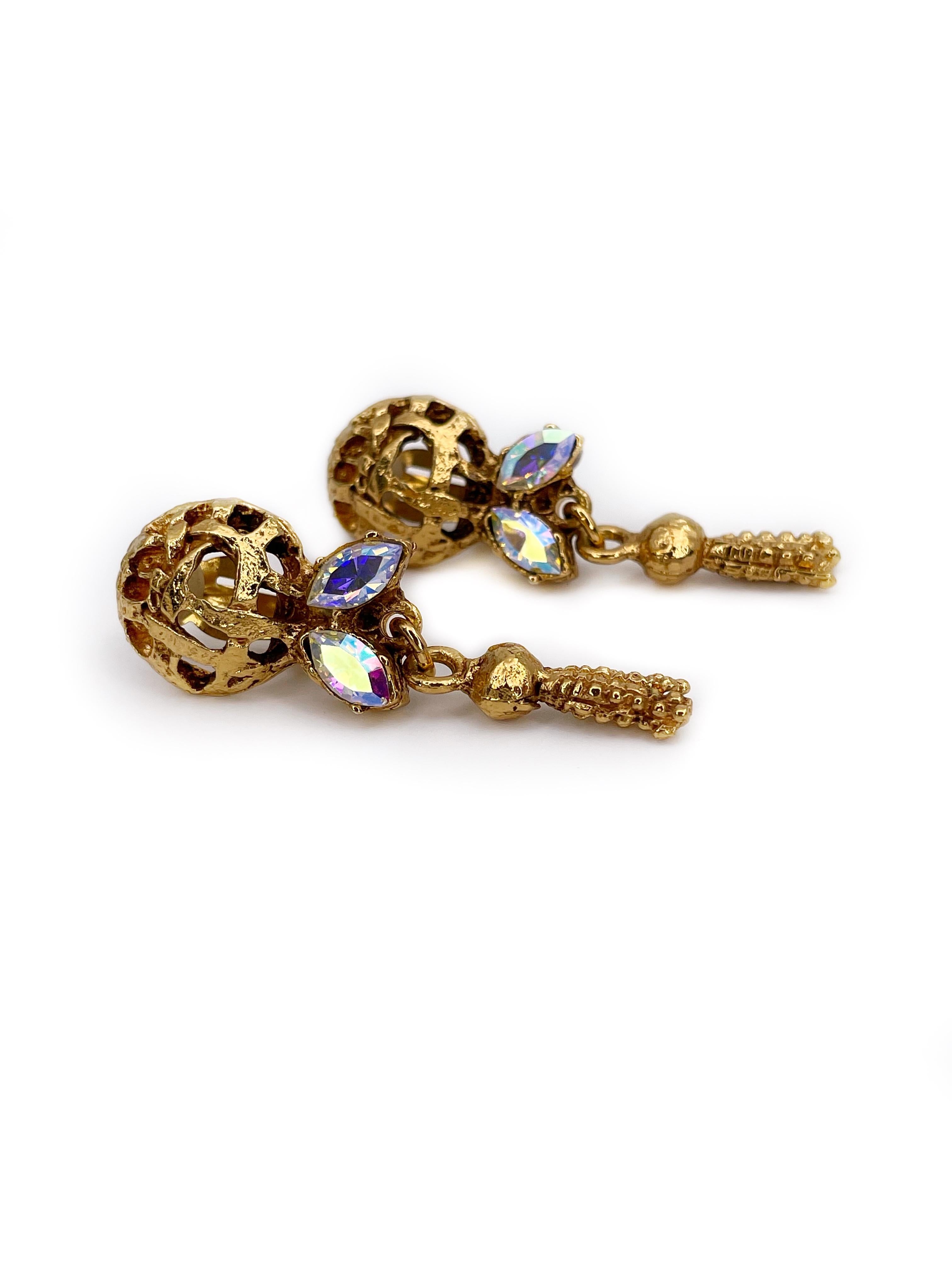 This is a shinny pair of earrings designed by Christian Lacroix in 1980’s. The piece is gold plated, decorated with four Aurora Borealis crystals. It features round openwork upper body and a dangling tassel motif. 

These clip on earrings could be a