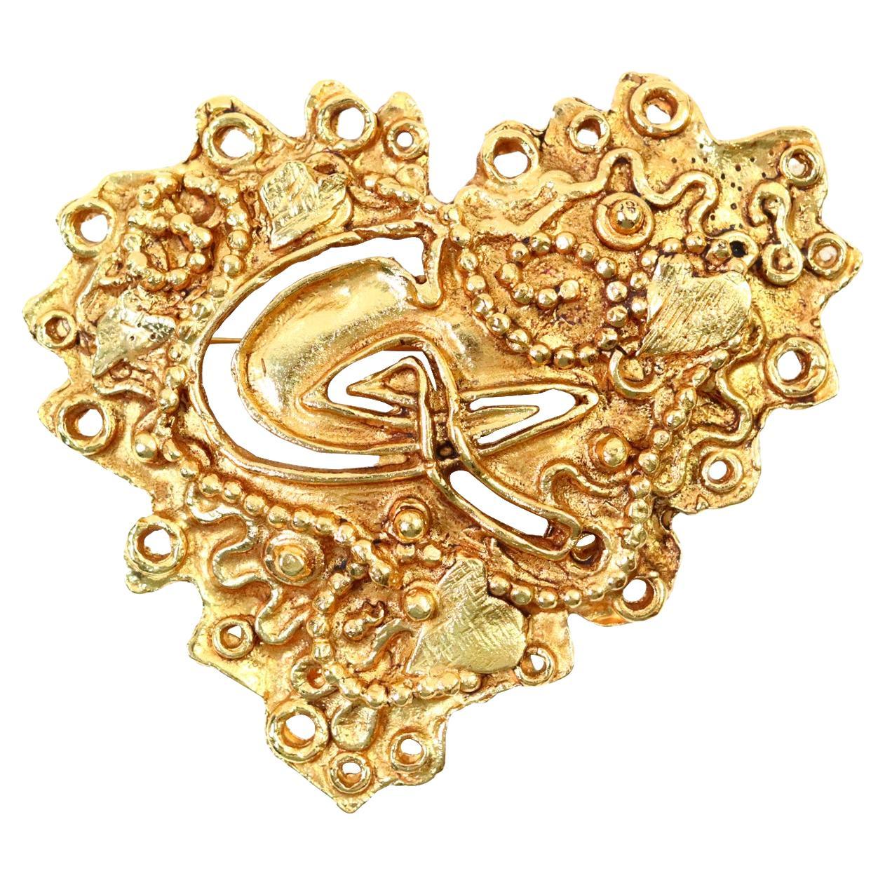 Vintage Christian Lacroix Gold Tone Heart Brooch with lots of Design and has Initials CL Carved in the Middle of the Misshapen Heart Brooch.  Matches a Bracelet that is on Site.  Same Interesting Texture. 

Lacroix says his fashion icon is The Queen