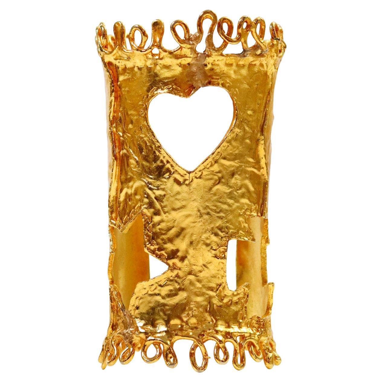Vintage Christian Lacroix Paris Gold Iconic Cutout Cuff Circa 1990.  La manchette présente une découpe de l'étoile, de la croix et du cœur, ainsi que des tourbillons en haut et en bas.  Manchette très emblématique.  Le métal est malléable, mais il
