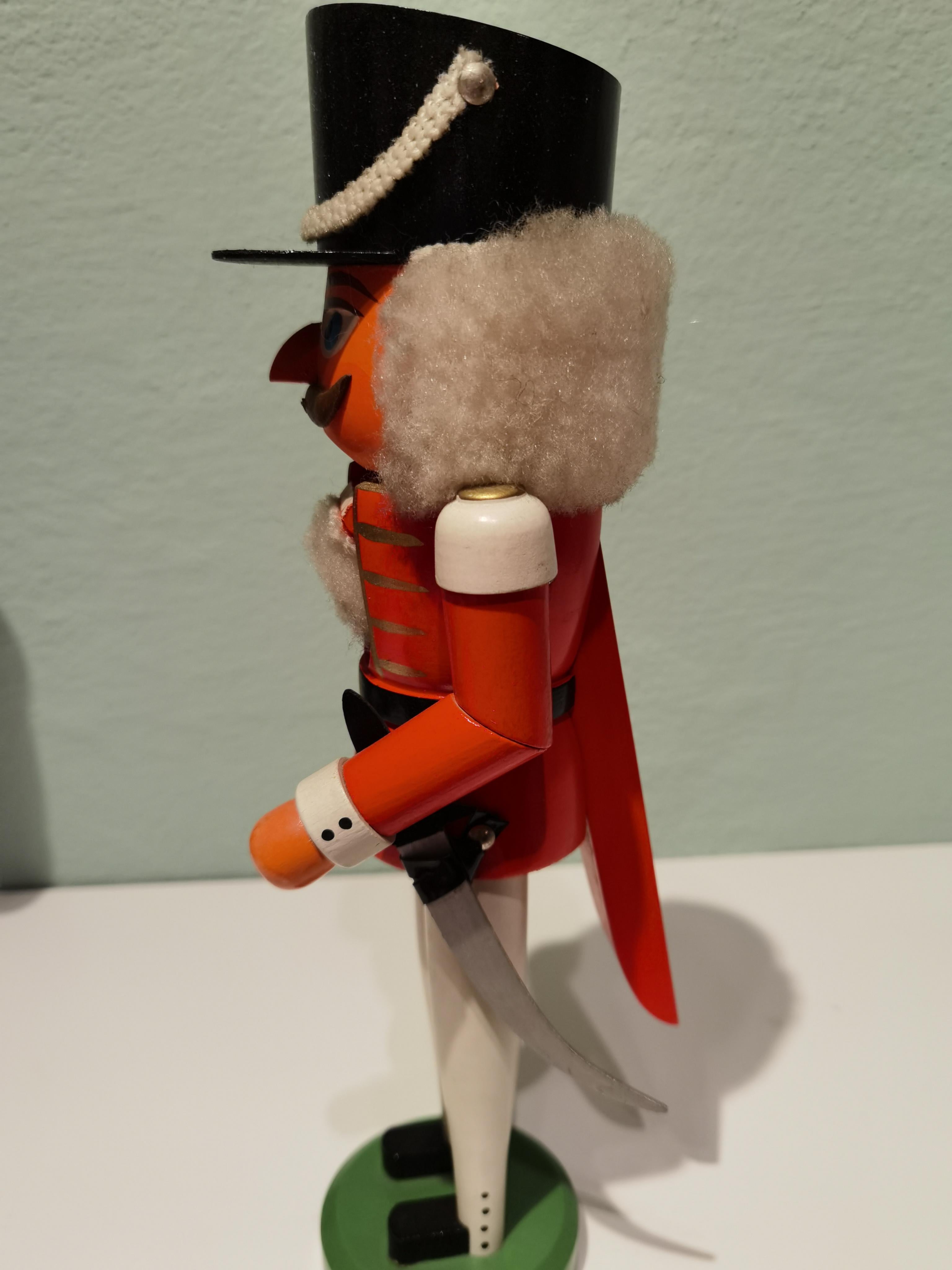 Large wooden nutcracker figure from the Erzgebirge. The region Erzgebirge formerly Eastern Germany is famous for this special kind of nutcrackers, where intricate carving has been their home. Completely hand painted in bright red and white colors