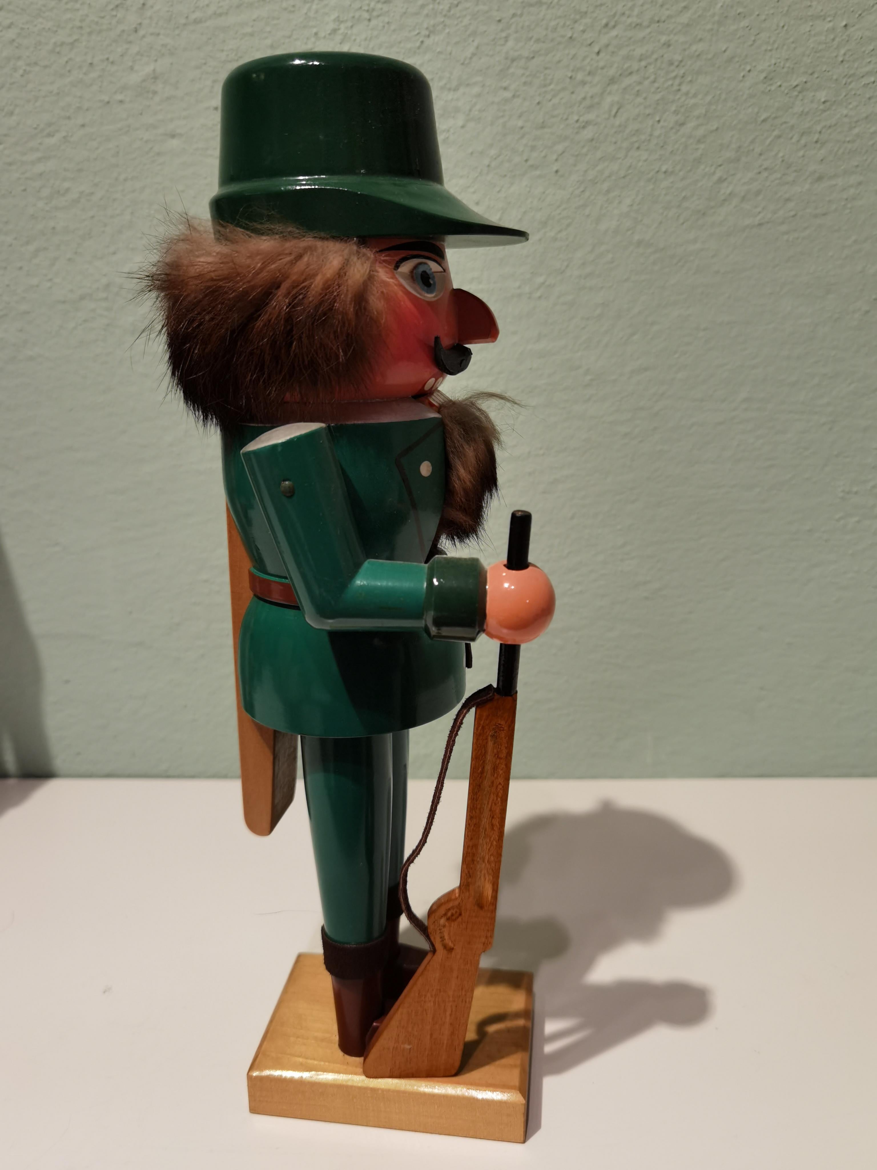 Large wooden nutcracker figure from the Erzgebirge. The region Erzgebirge formerly Eastern Germany is famous for this special kind of nutcrackers, where intricate carving has been their home. Completely hand painted in bright green colors and