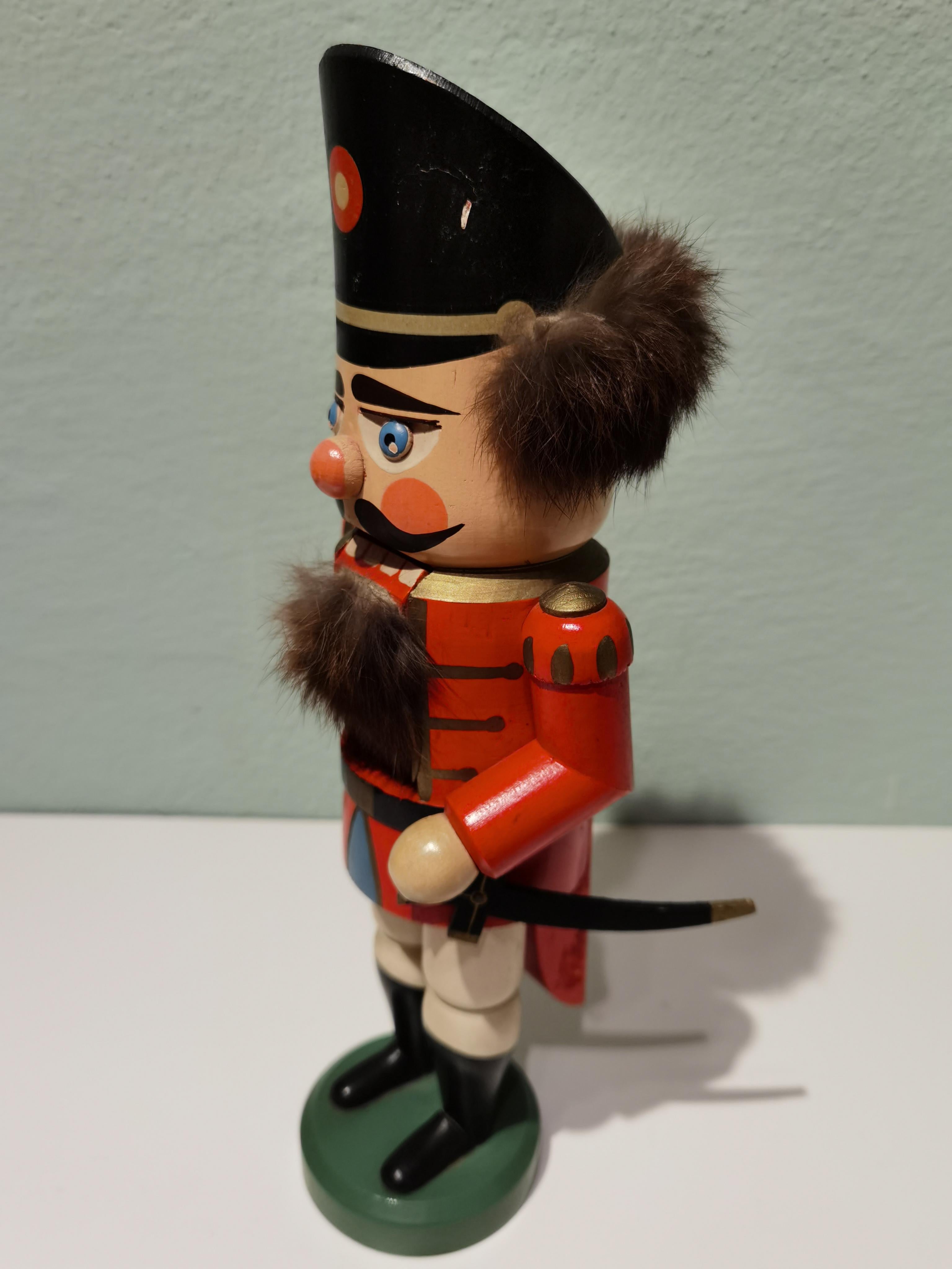 Large wooden nutcracker figure from the Erzgebirge. The region Erzgebirge formerly Eastern Germany is famous for this special kind of nutcrackers where intricate carving has been their home. Completely hand-painted in bright red colors and decorated