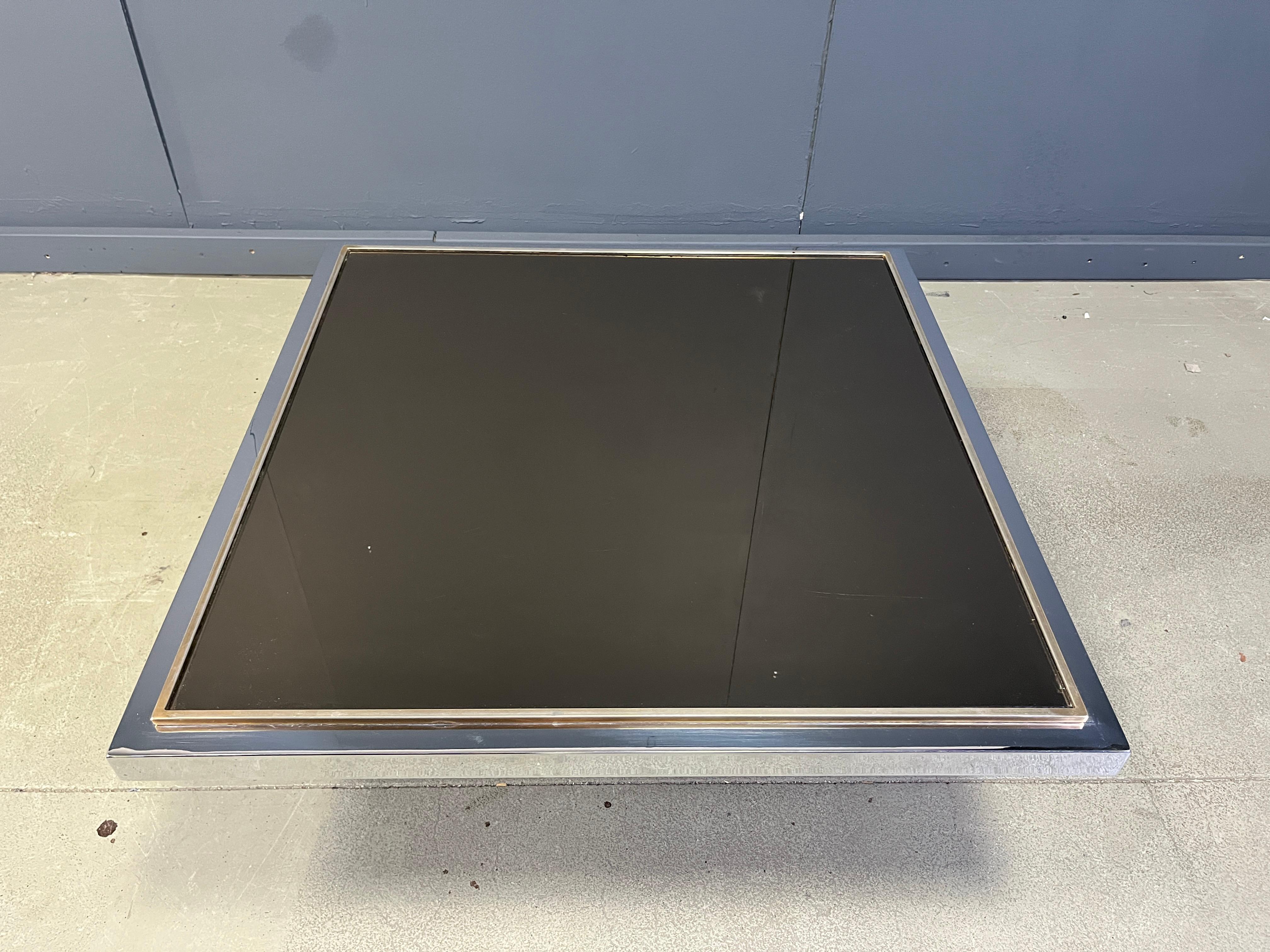Table basse vintage fabriquée par Belgochrom/Dewulf By qui a produit des meubles de luxe haut de gamme jusqu'au début des années 2000.

Cette table basse est composée d'une base en bois noir et d'un plateau en chrome et laiton avec un verre miroir