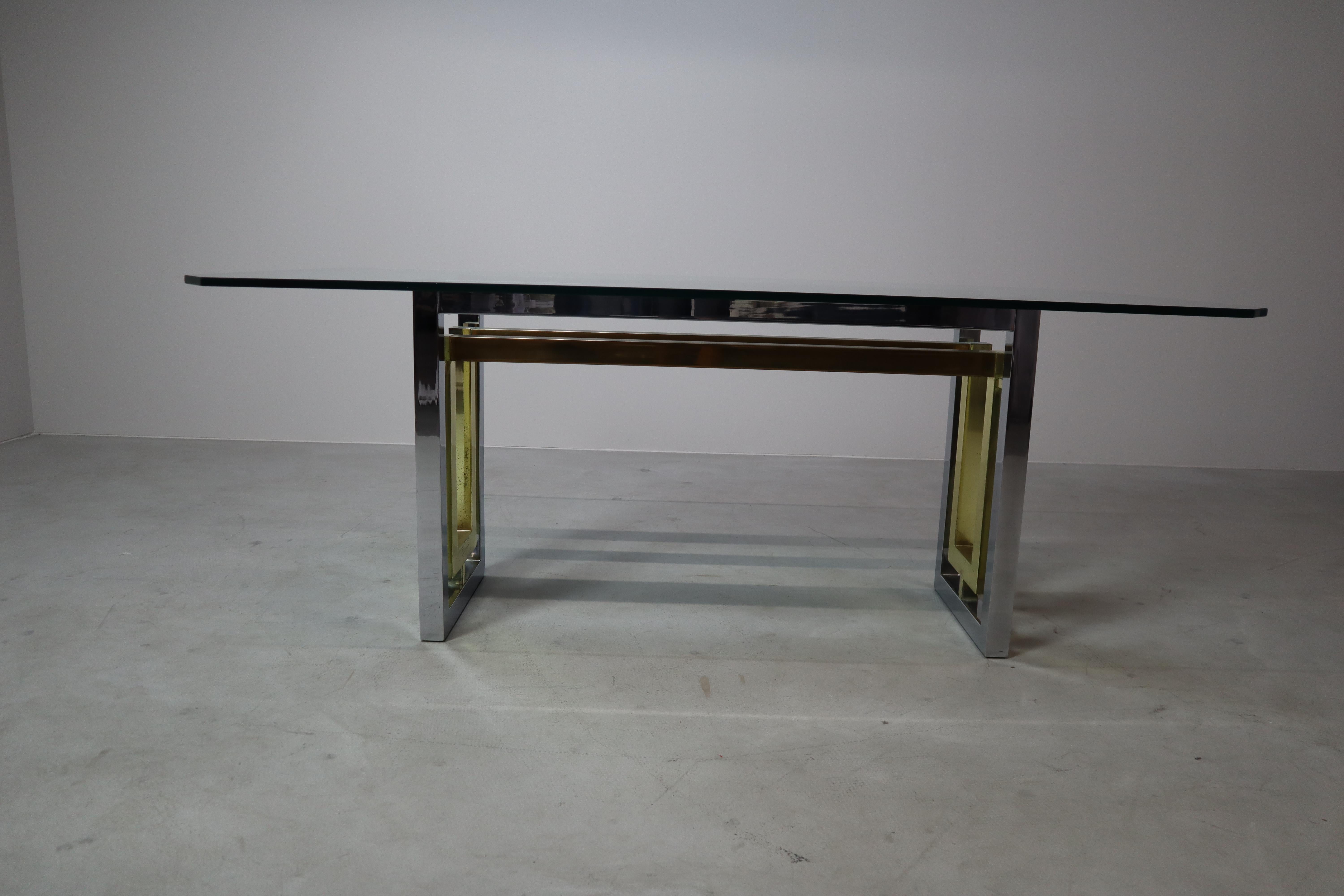 Table de salle à manger étonnante produite par Zevi en Italie dans les années 1970. La pièce se compose d'une base rectangulaire en métal chromé et en laiton supportant un épais plateau en verre biseauté avec des coins angulaires. Le cadre