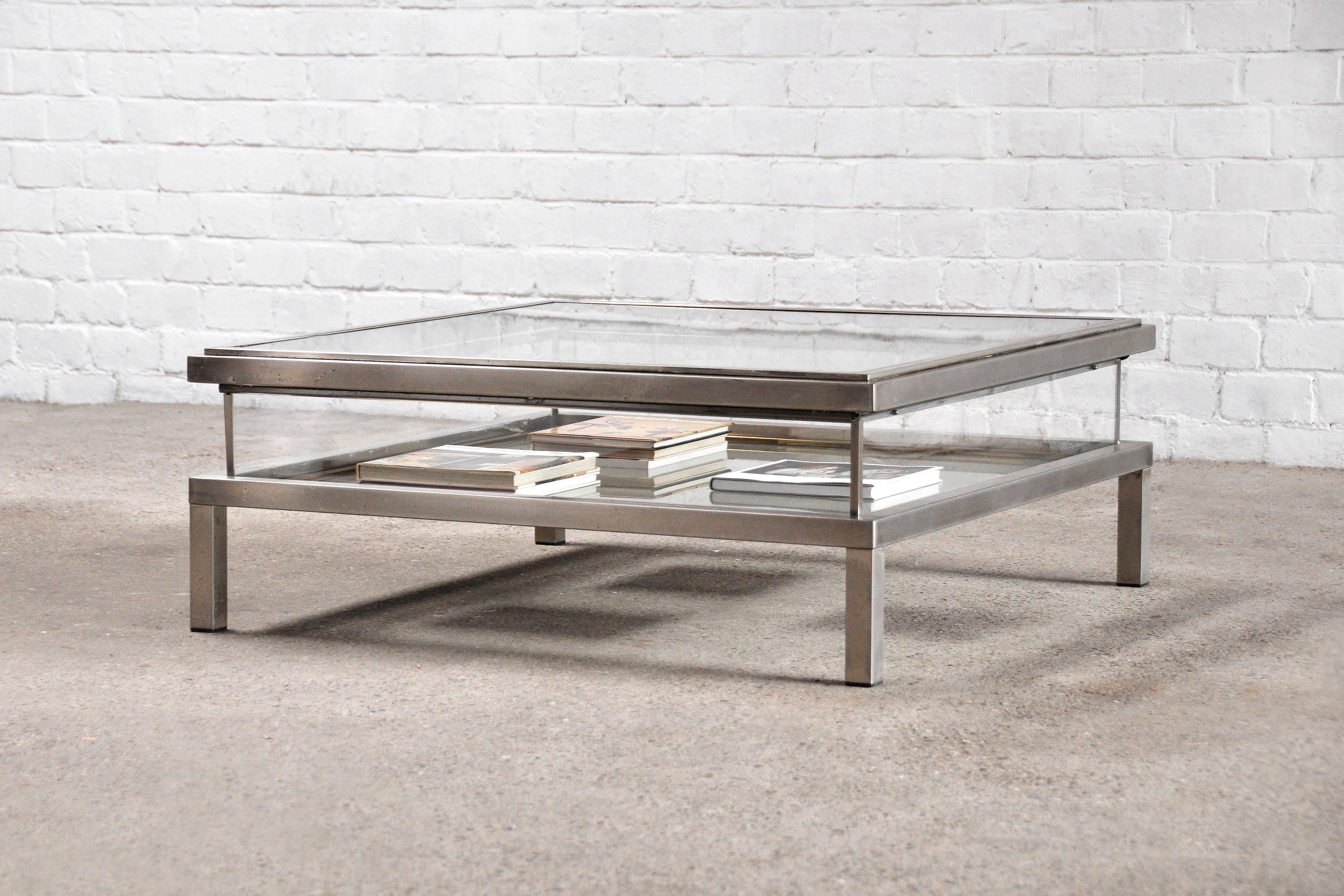 Large square glass table with sliding top by Maison Jansen. The coffee table has the ability to slide open which allows one to store magazines or other objects. The framed is made out of chromed steel with brass plated finishes.

The table is in