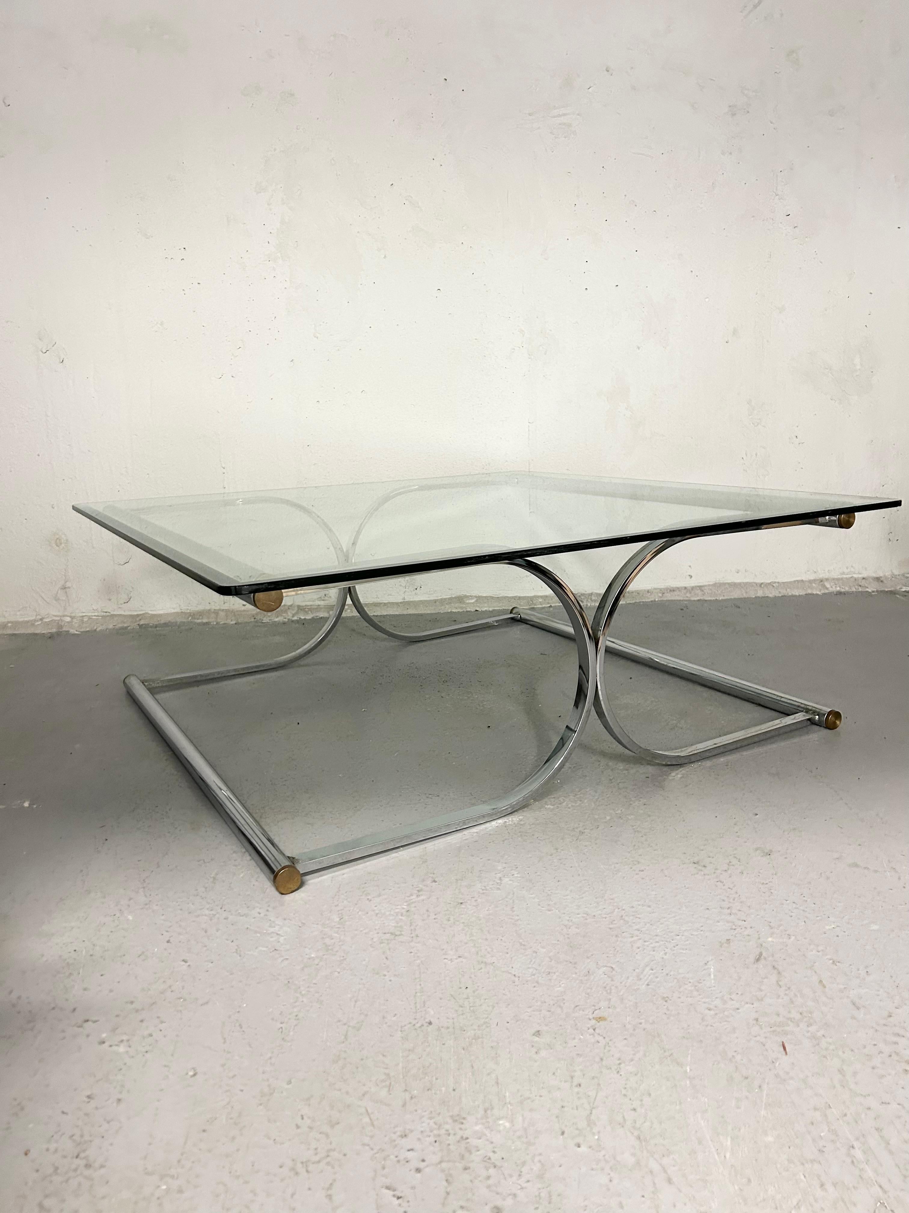 Vintage chrome and glass cantilever coffee table. Base is sculptural - made of tubular chrome and has brass end caps. Square glass top sits on top. Glass has beveled edge. Chrome base has minimal wear. Glass top has normal surface wear. One very