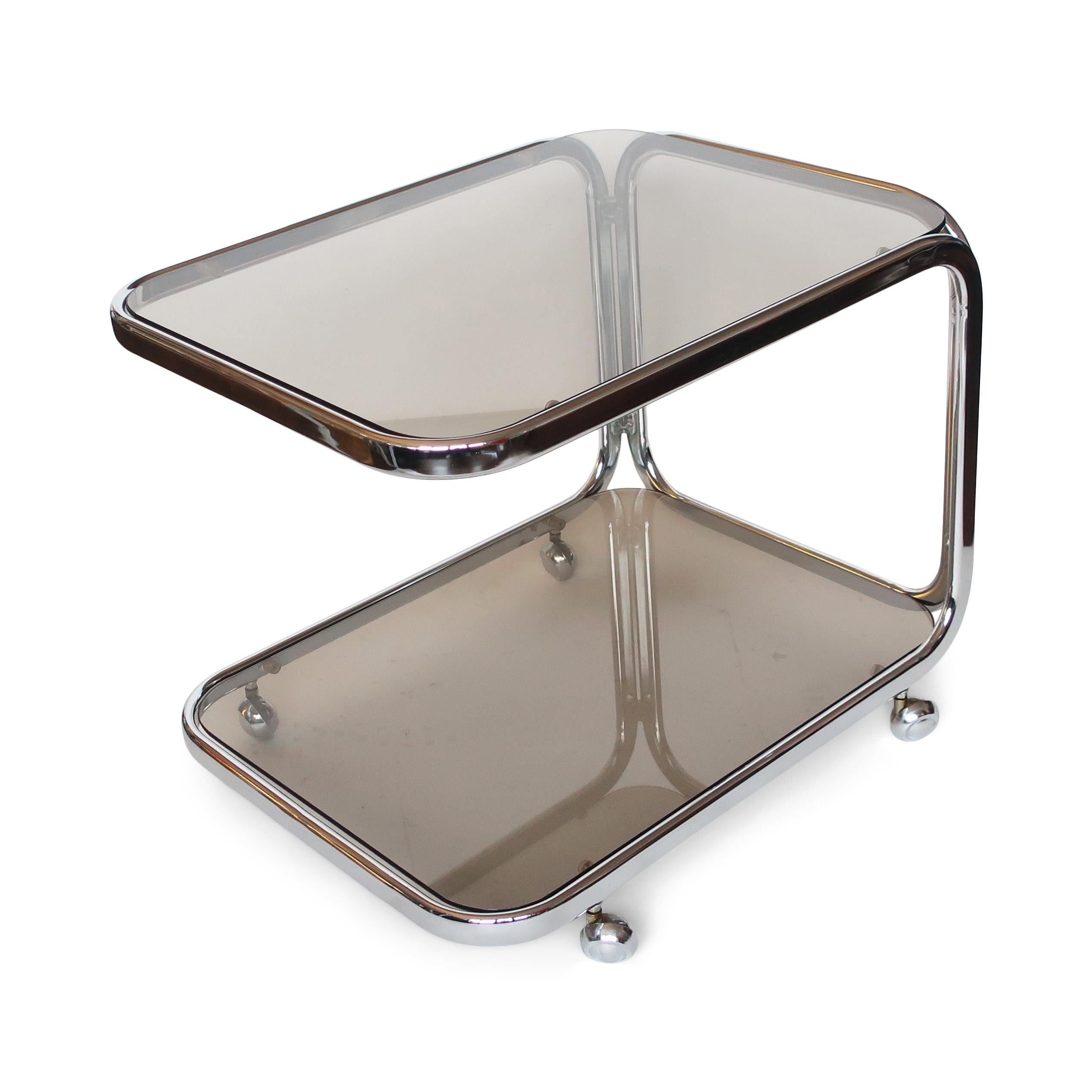 An exceptional vintage chrome and smoked glass bar cart that couldn’t be much more perfectly vintage 1970s. Sensuous curved chrome lines, chrome casters, and two mysterious and smokey glass shelves. The two tiers of the drinks cart provide plenty of