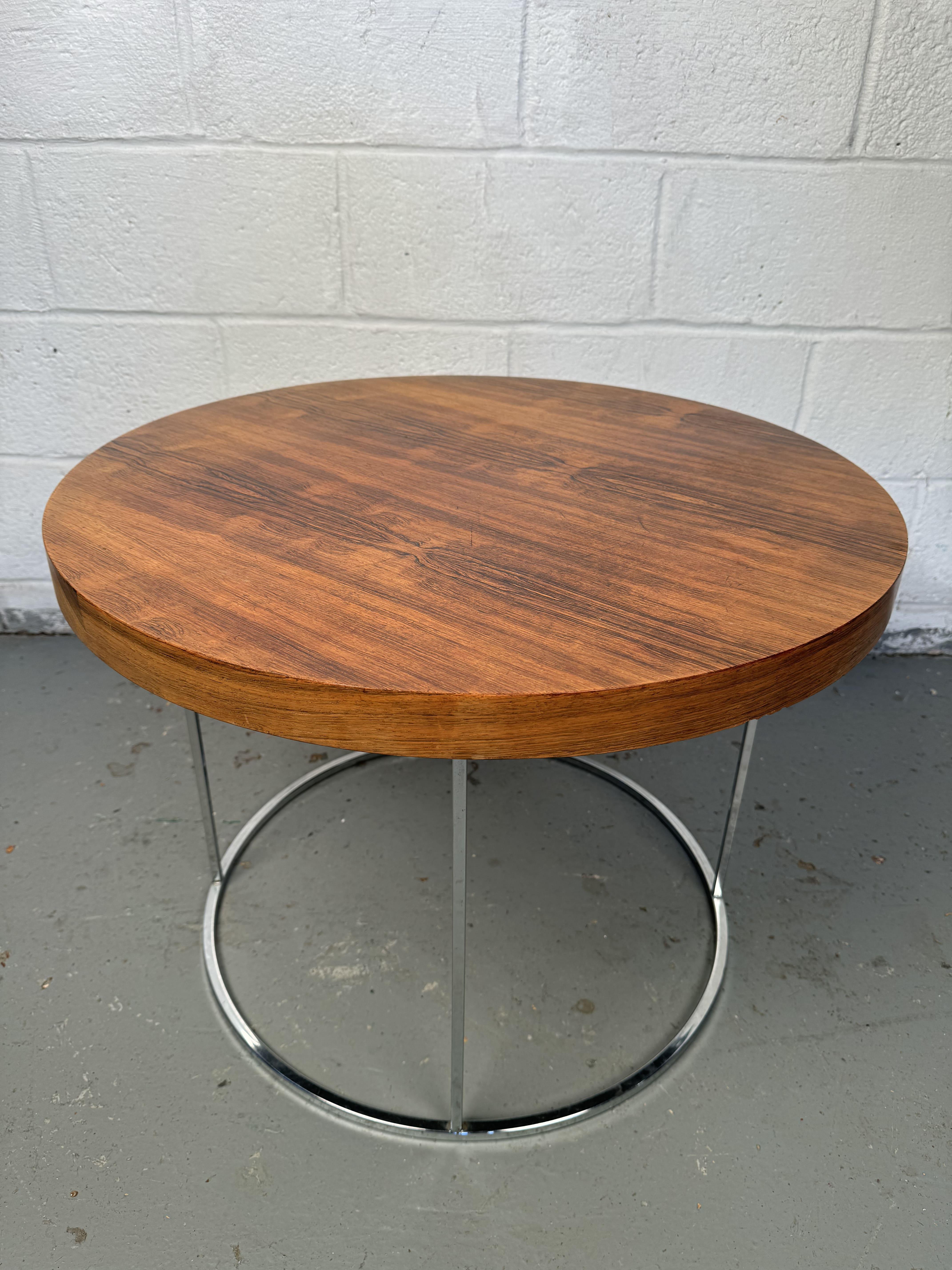 Vintage Beistelltisch aus Chrom und Holz. Mit seinem eleganten Chromgestell, das einen schönen Kontrast zu den warmen Tönen der Holzplatte bildet, verkörpert dieses Stück zeitlosen Stil und Funktionalität. Die klaren Linien und das minimalistische