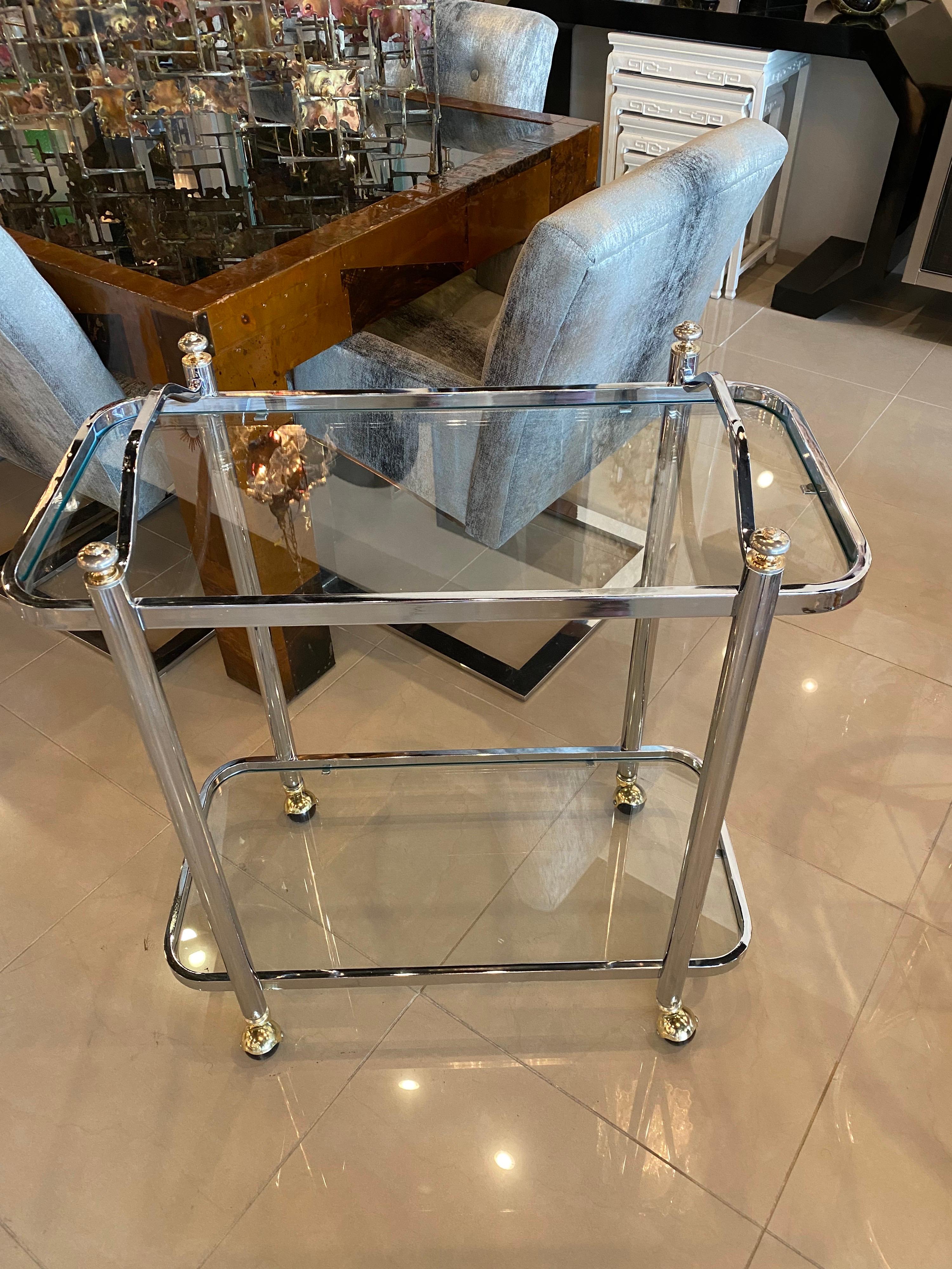 Lovely chrome and brass Barcart. Two glass shelves. The glass has been newly cut. The chrome and brass have been polished. The heavy brass castors are new as well. Dimensions: 32 H (to handles) x 16 D x 30.25 L. Height to top shelf is 29.25.