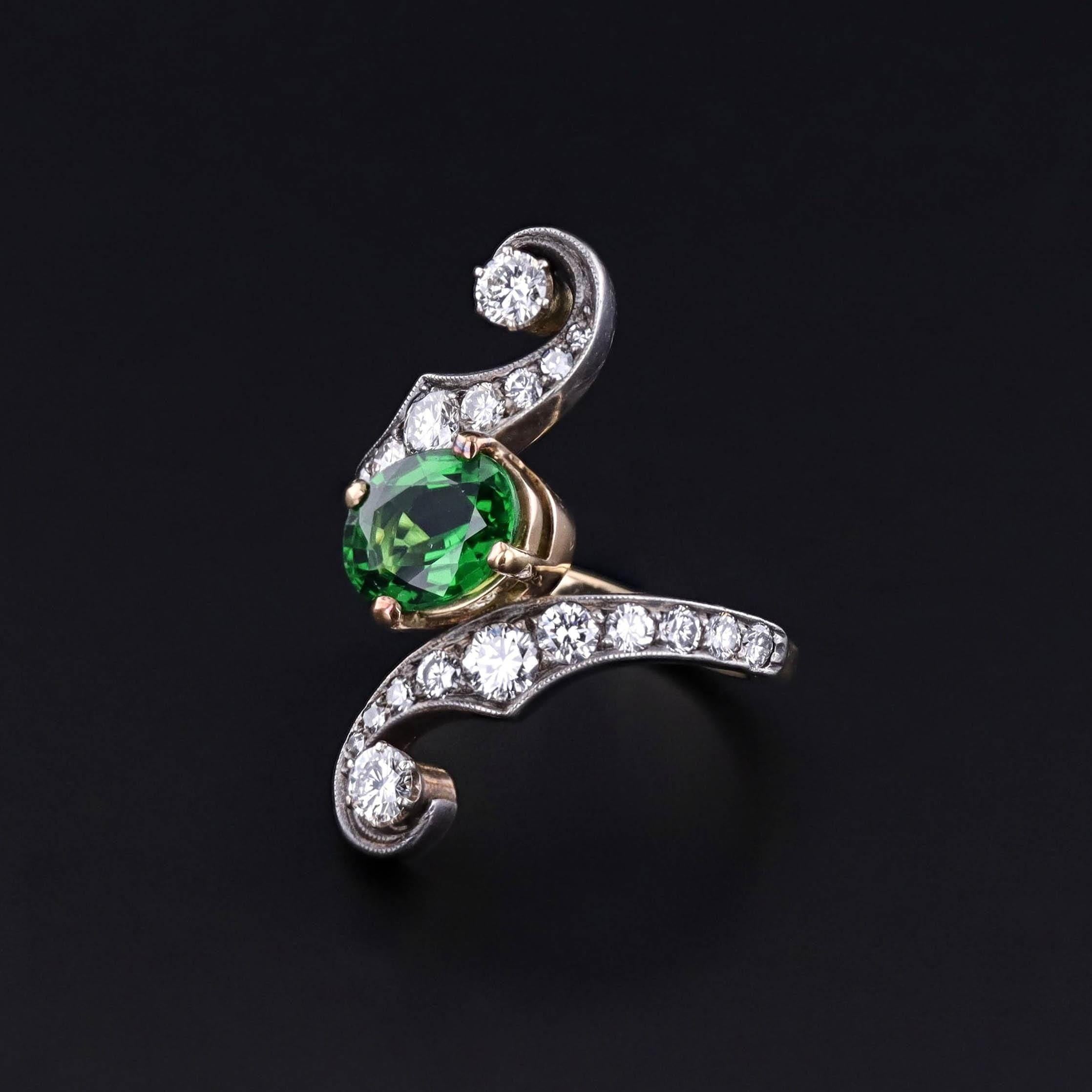 Vintage Tourmaline Ring: This dramatic crossover ring (circa 1960-1970) features a 1.34ct vivd green chrome tourmaline with 22 brilliant diamonds totally approximately 0.70ct H clarity VS/SI clarity. The ring is silver topped 18k gold.

The band is