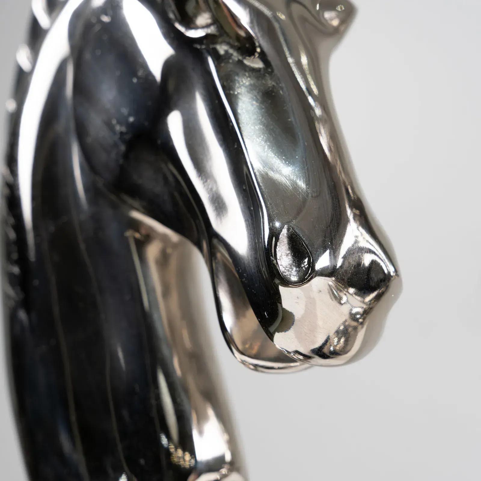This stunning pair of table lamps features sculptural horse-head designs in polished chrome atop sleek black bases.