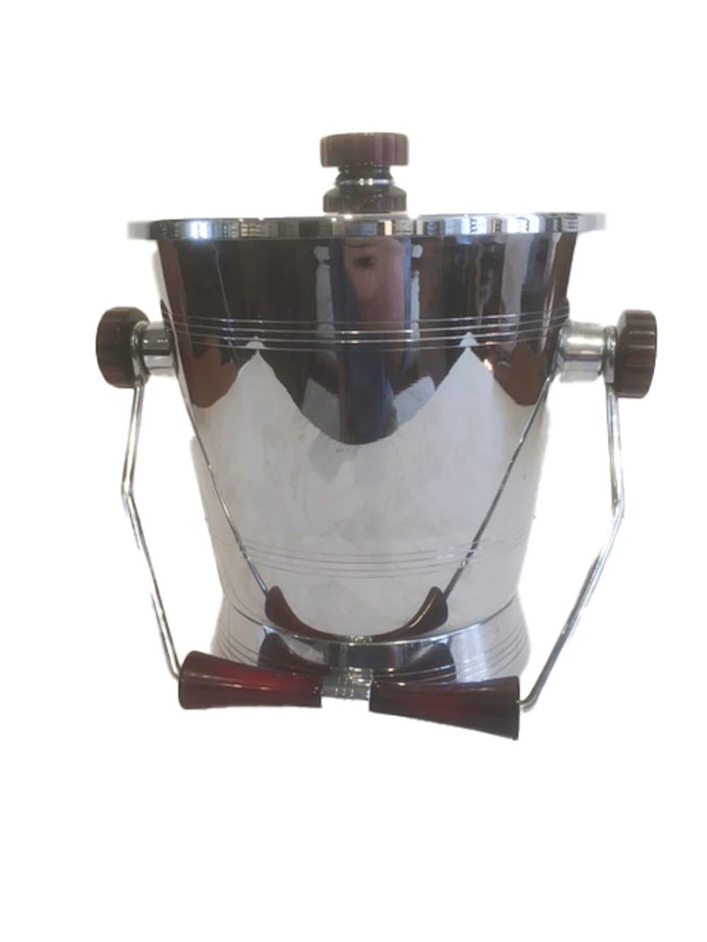 Mid twentieth century chrome plated ice bucket with red Bakelite handles and knobs along with a pair of ice tongs with Bakelite side panels. Made by Glo-Hill as part of their Barmates line.