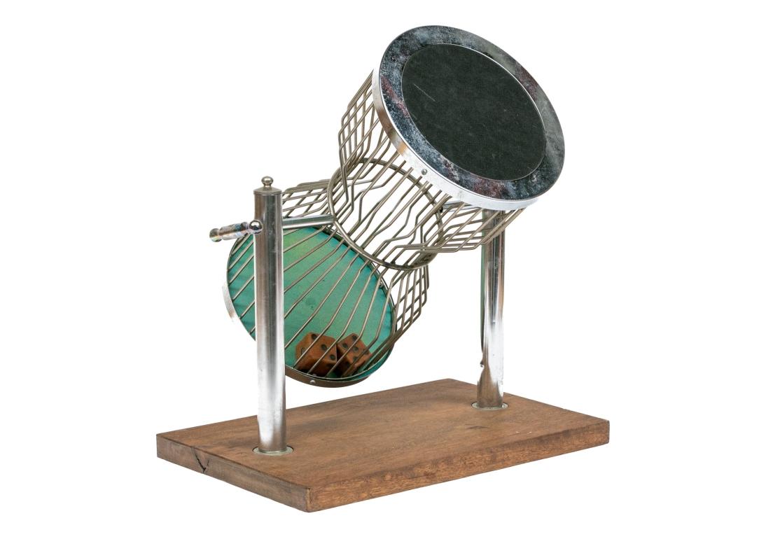 An hour-glass form chrome housing mounted on a rotating handled frame and surmounted on a wood plinth.
The housing contains two large 1 1/2