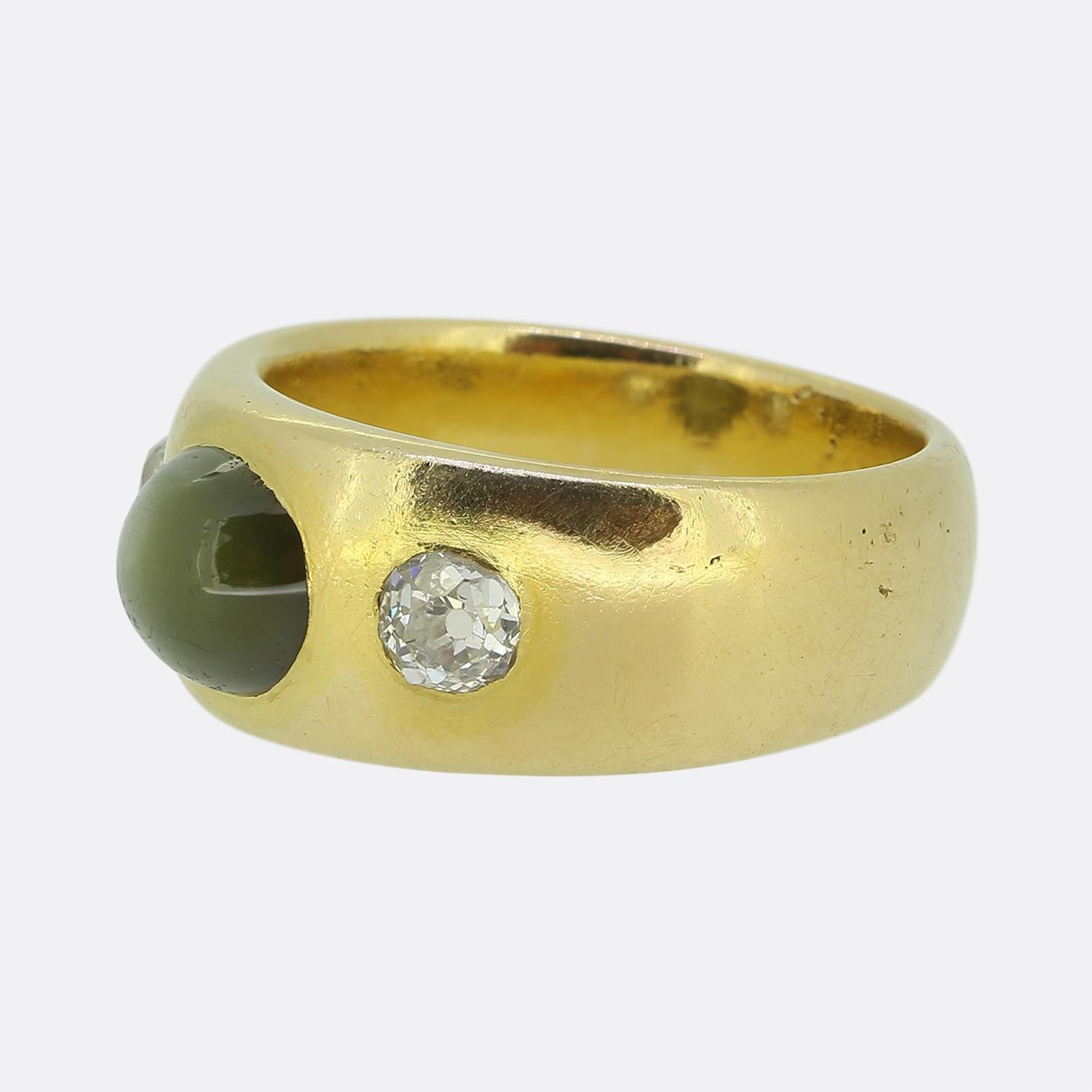 Here we have a chic and stylish three stone ring. This vintage piece features a single cats eye chrysoberyl at the centre of the face with a chunky old mine cut diamond flanking on either side. All stones here have been bezel set atop a wide 18ct