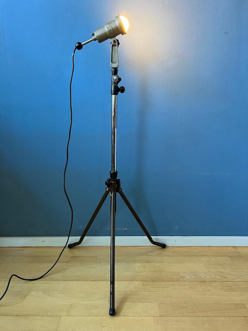 Vintage Cifo photography spotlight floor lamp. The lamps has a tripod-style base, similar to the stands used for old cameras and studio lighting equipment. The lamp has an adjustable height feature, allowing you to raise or lower the lamp to your