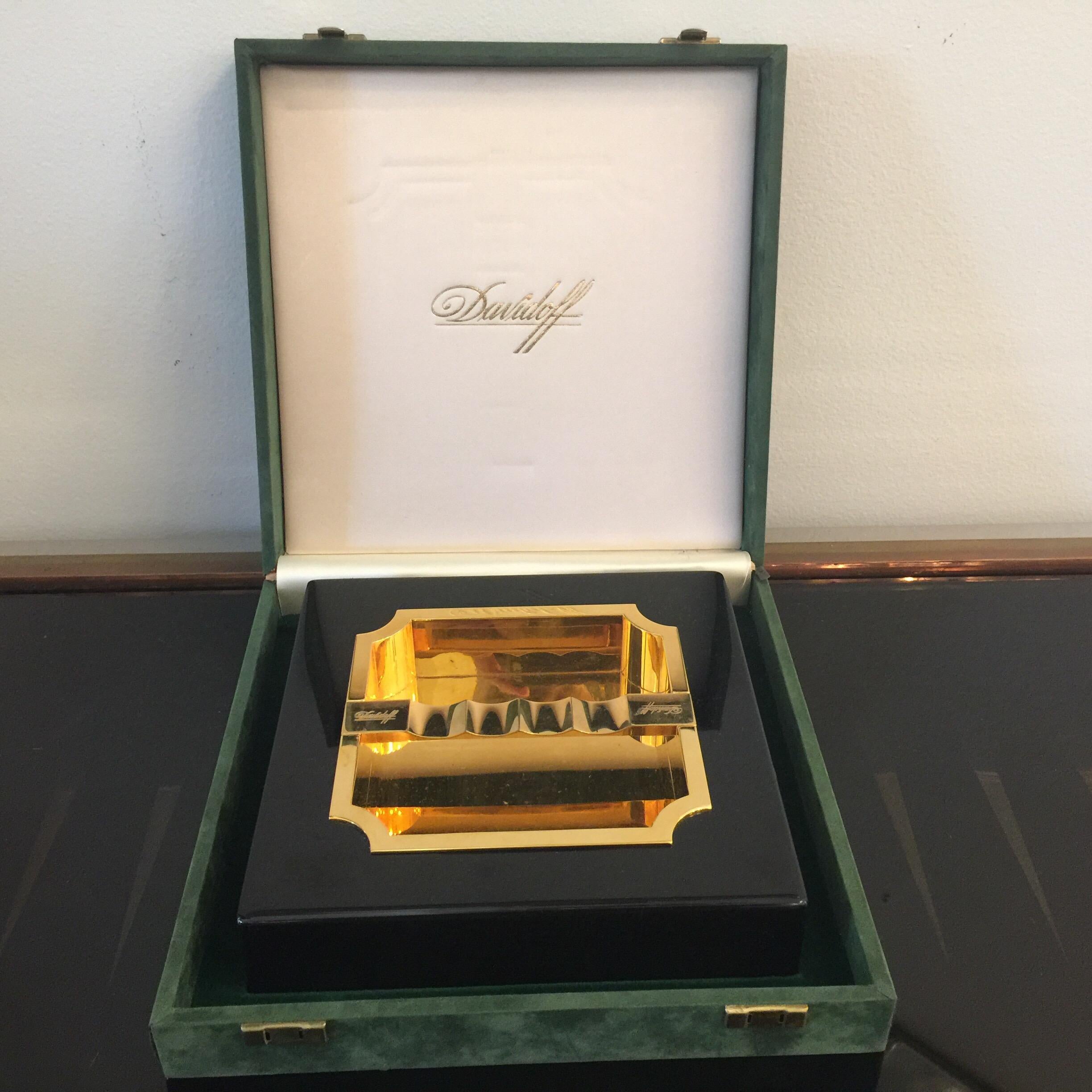 In its original velvet clad box, this unused gold-plated metal and black resin cigar ash tray by Davidoff is a rare find. Mad Men period luxury item!