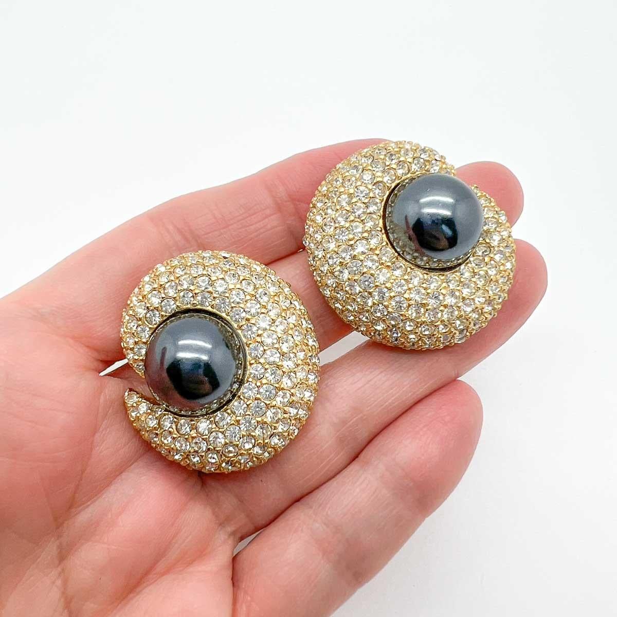 Vintage Ciner Pearl Crescent Earrings. Avec une perle grise merveilleusement opulente au milieu d'un croissant de cristal.
Depuis 1982, la société CINER, basée à New York, conçoit et fabrique des bijoux fantaisie. Se détournant de la production de