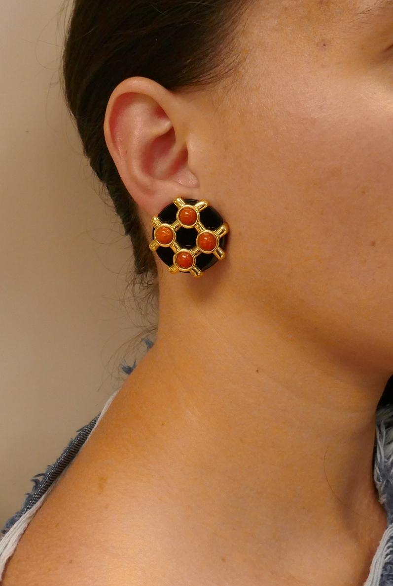 Signature ear-clips created by Aldo Cipullo in 1972. 
Made of black onyx, coral and 18k (stamped) yellow gold. Sharp geometrical design and dramatic color combination are the highlights of these stylish earrings. 
Measurements:  diameter 1-1/8