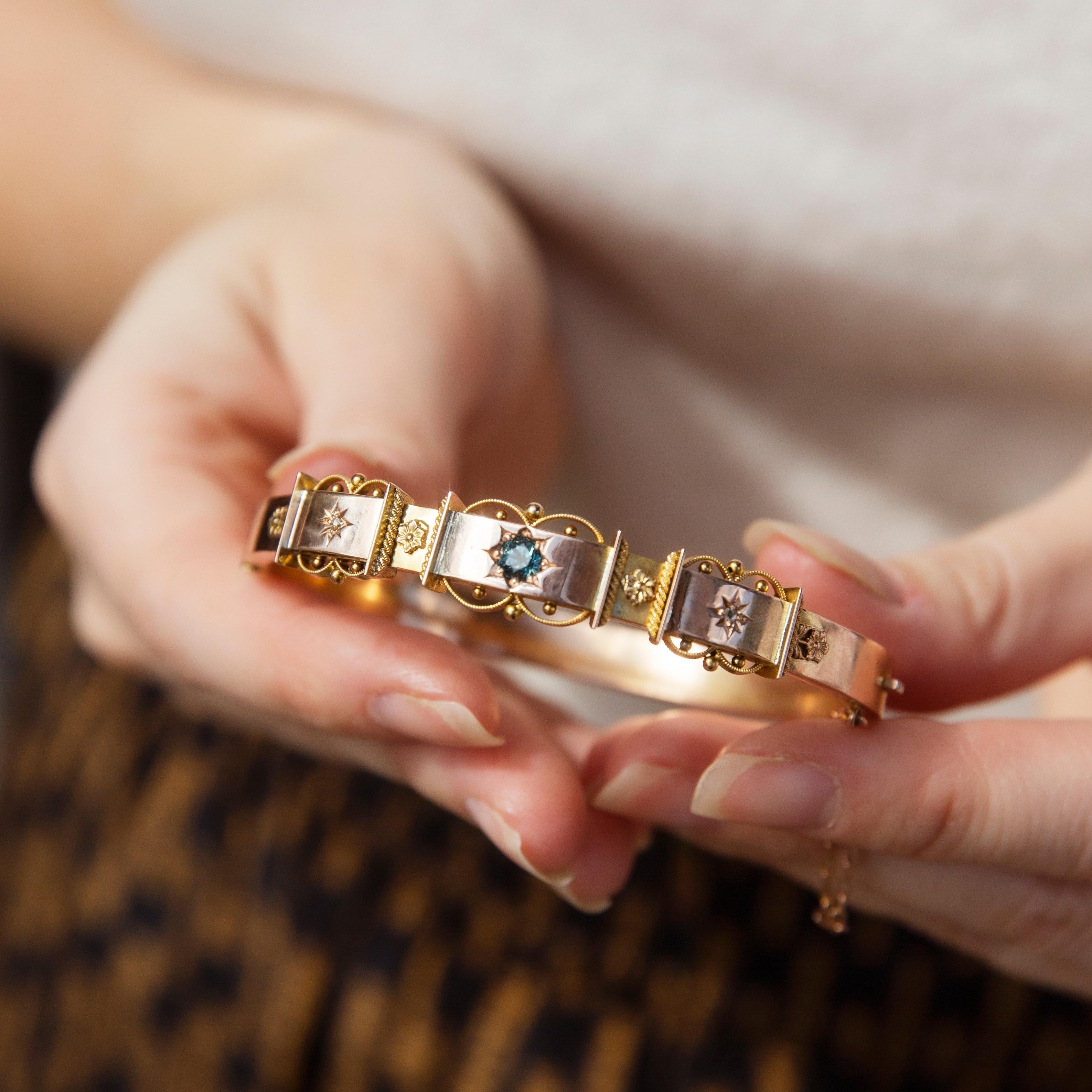 Whisperings of days gone by, The Easton Bangle is a vintage delight. Her alcoves of contrasting golds embellished with wildflowers and stars are set with a rich green sapphire and shimmering diamonds. The finishing touch of a fine lace of ribboning