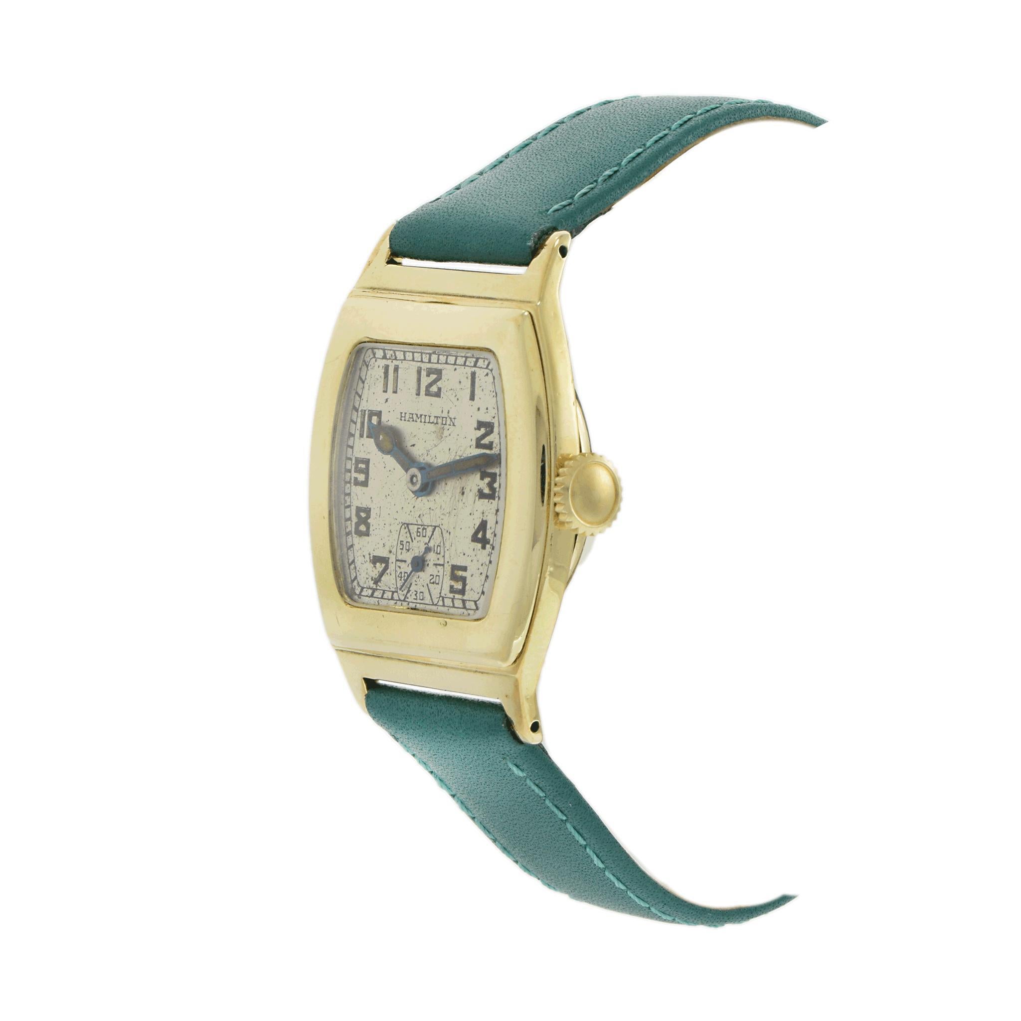 A classic circa 1940 Hamilton dress watch, featuring a 28mm x 33mm curved 14KT yellow gold-filled case, designed for a refined and comfortable fit. The silver dial is elegantly adorned with Arabic numeral markers and a sub-dial for seconds,