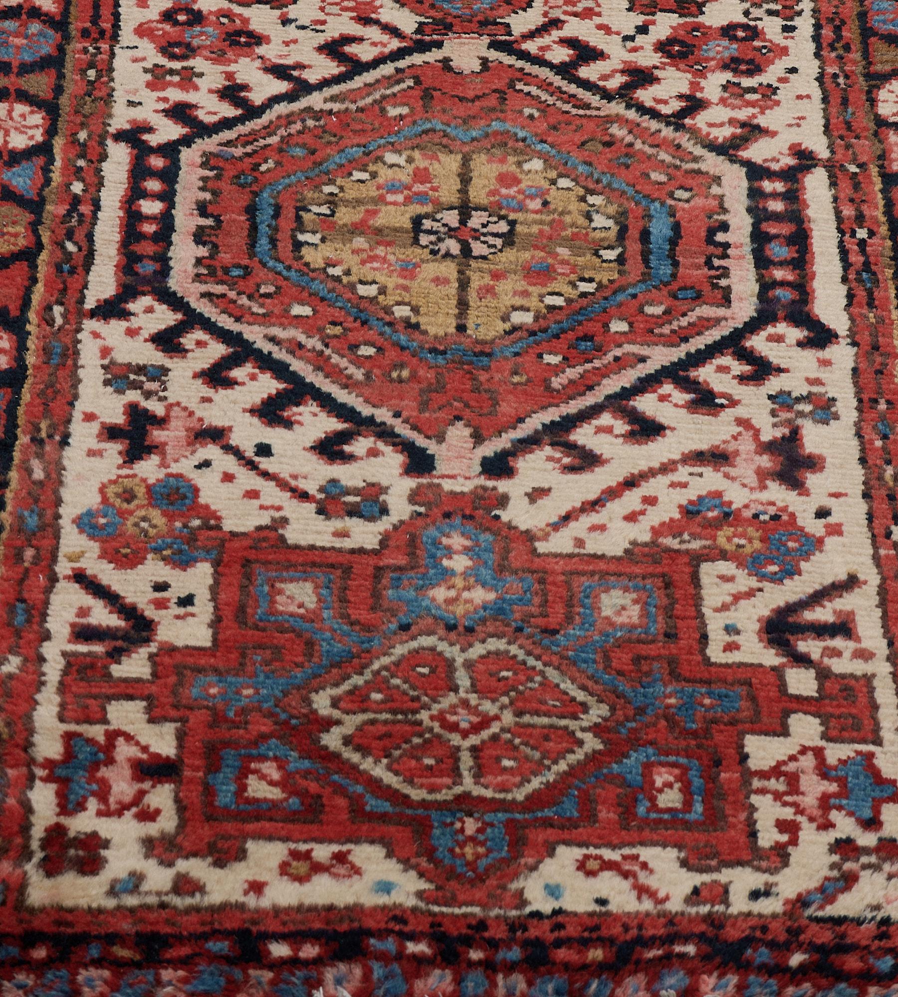 Dieser um 1940 entstandene persische Heriz-Läufer hat ein elfenbeinfarbenes Feld mit einer Vielzahl von zarten, eckigen Blumenmotiven um eine zentrale Säule aus miteinander verbundenen hellblauen Stufenrauten mit einer zentralen elfenbeinfarbenen