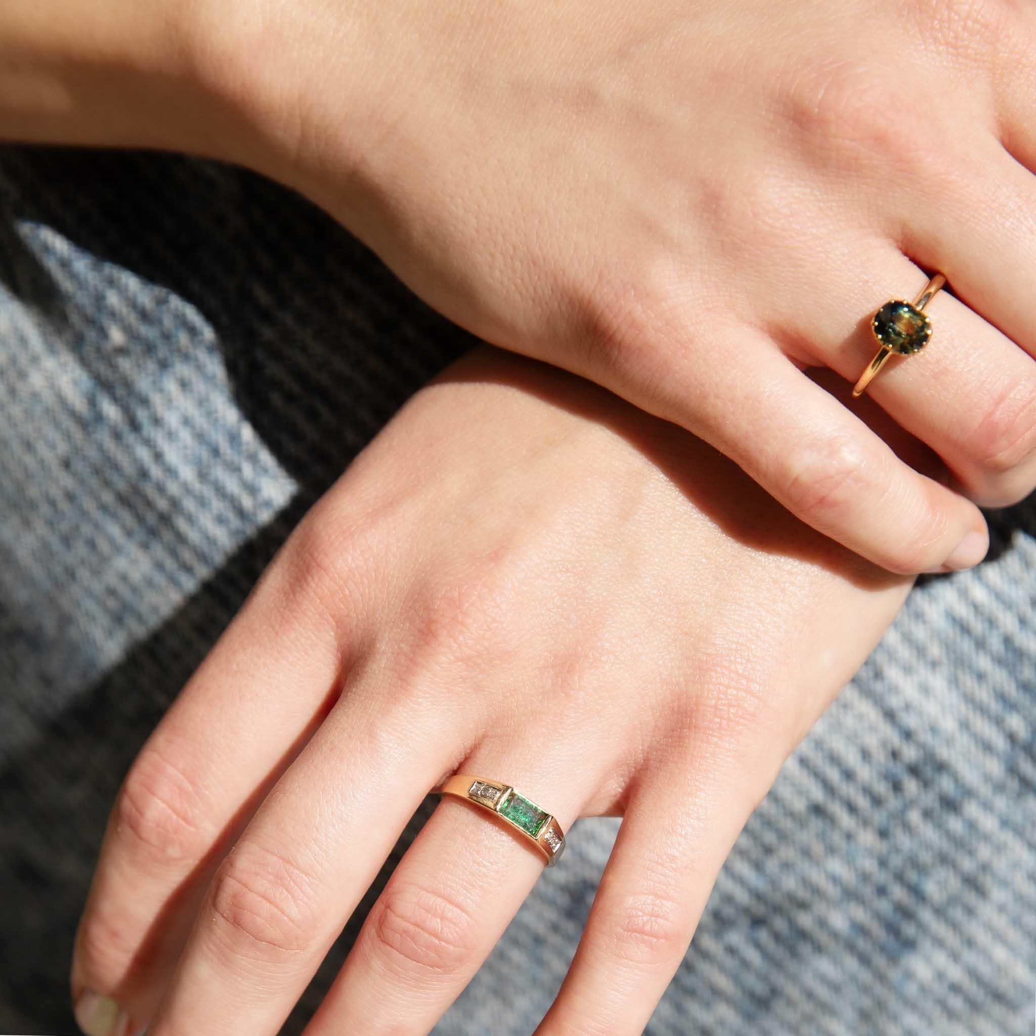 Her forest green solitary sapphire, a gem of verdant depths, rests regally within a crown of luminous 18 carat gold. The union is flawless, a symphony of color and brilliance. Meet our Brooklyn Ring, an unassuming yet captivating jewel, a whisper of