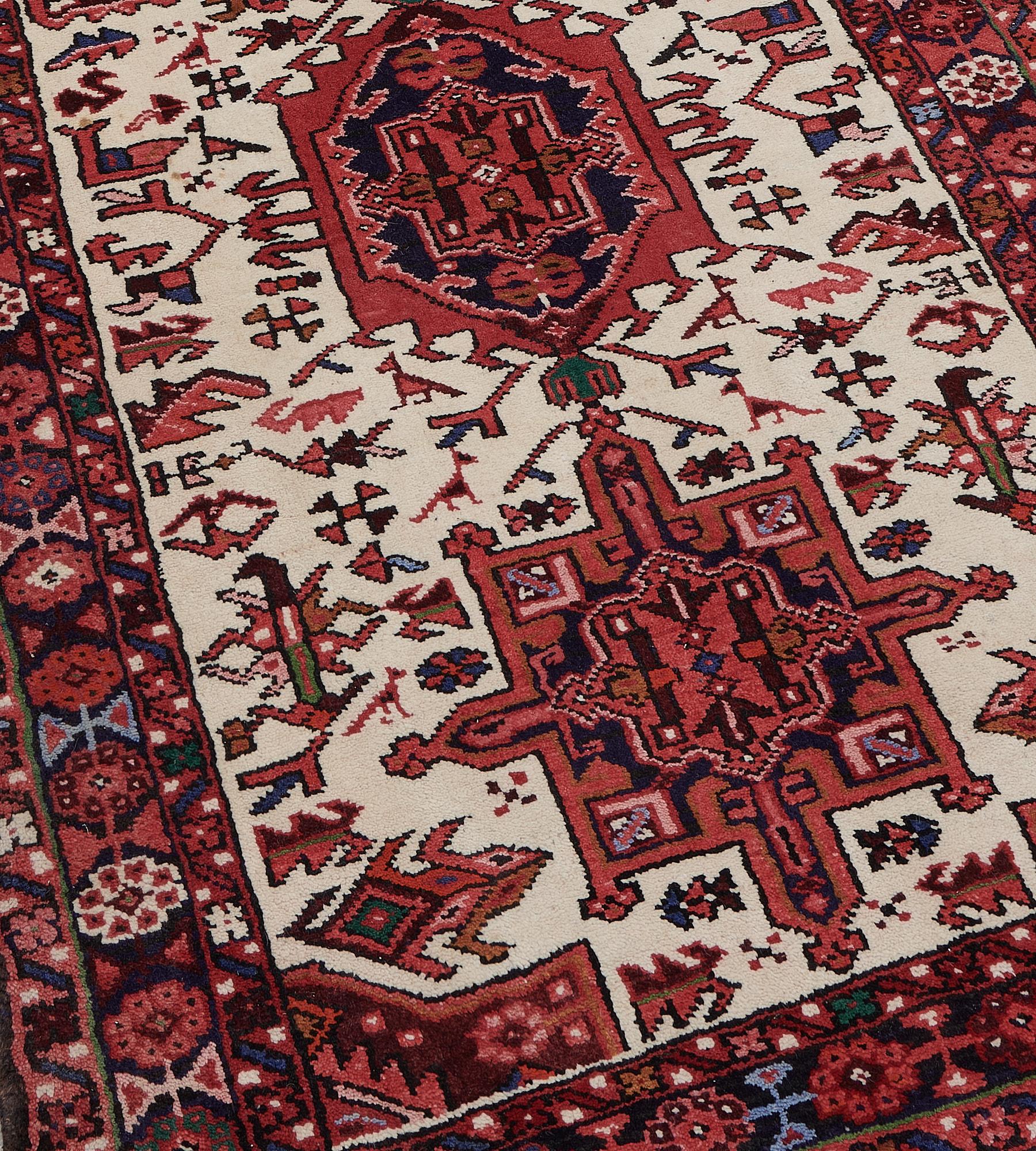 This vintage, circa 1960, Heriz runner has an ivory field with a central column of linked brick-red and indigo hooked shield lozenges surrounded by angular polychrome stylized floral and animal motifs, in an indigo-blue border of polychrome linked