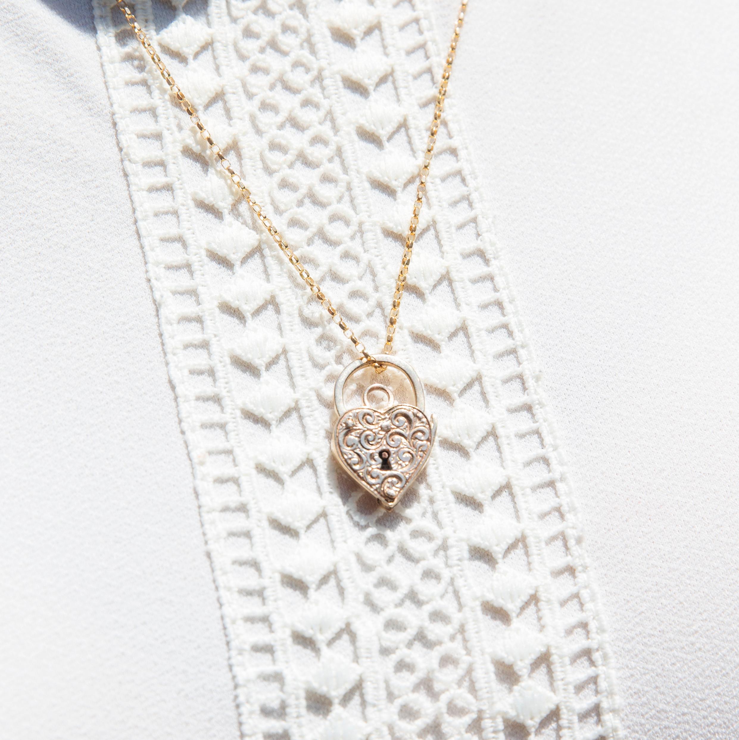 Notre cadenas et chaîne Carly, datant des années 1960, a été réalisé avec soin en or 9 carats. Son pendentif en forme de cœur est magnifiquement orné de rubans d'or tourbillonnants. Elle est un cadeau exquis pour l'être aimé, où votre cœur peut