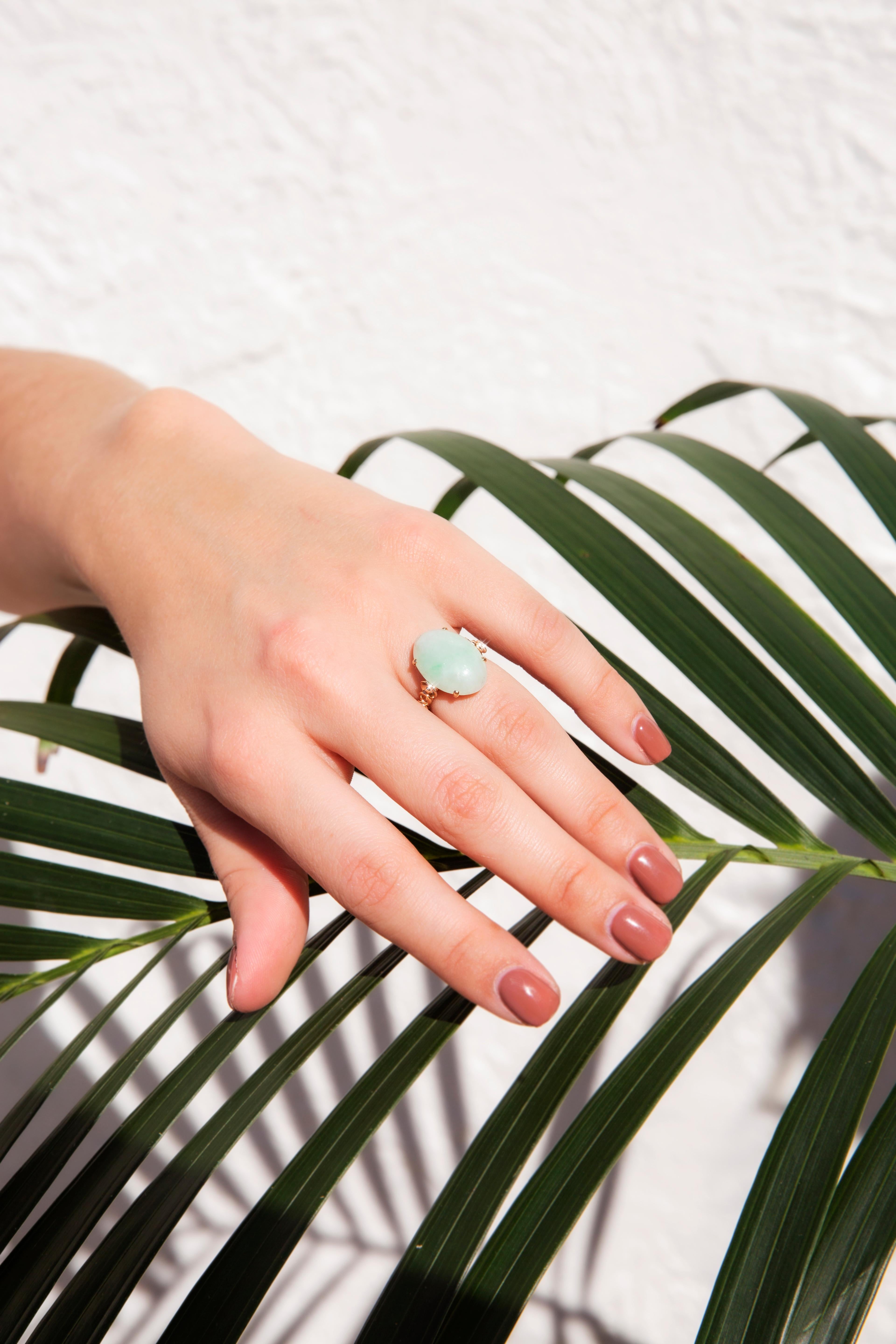 Dieser bezaubernde Vintage-Ring aus 14 Karat Gelbgold enthält einen hellgrünen, ovalen Jadeit im Cabochon-Schliff in einer Korbfassung mit vier Krallen auf kunstvoll gerahmten Schultern. Dieses anmutige Schmuckstück trägt den Namen 