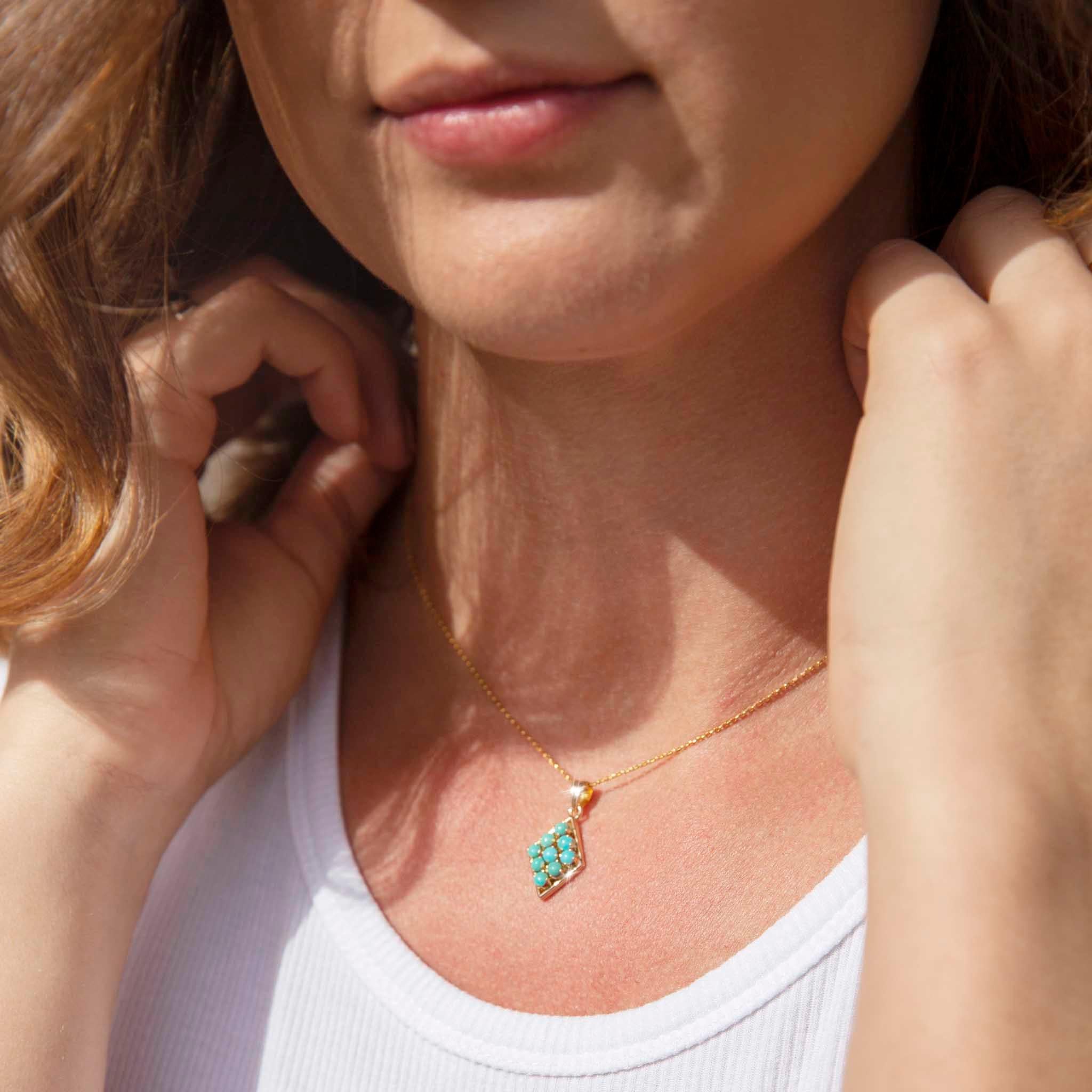Forged in 14 carat yellow gold, this charming vintage pendant features an elegant diamond-shaped setting holding nine round blue turquoise. The pendant is threaded on a fine 9 carat gold chain. We have named this darling pendant The Nuri Pendant and