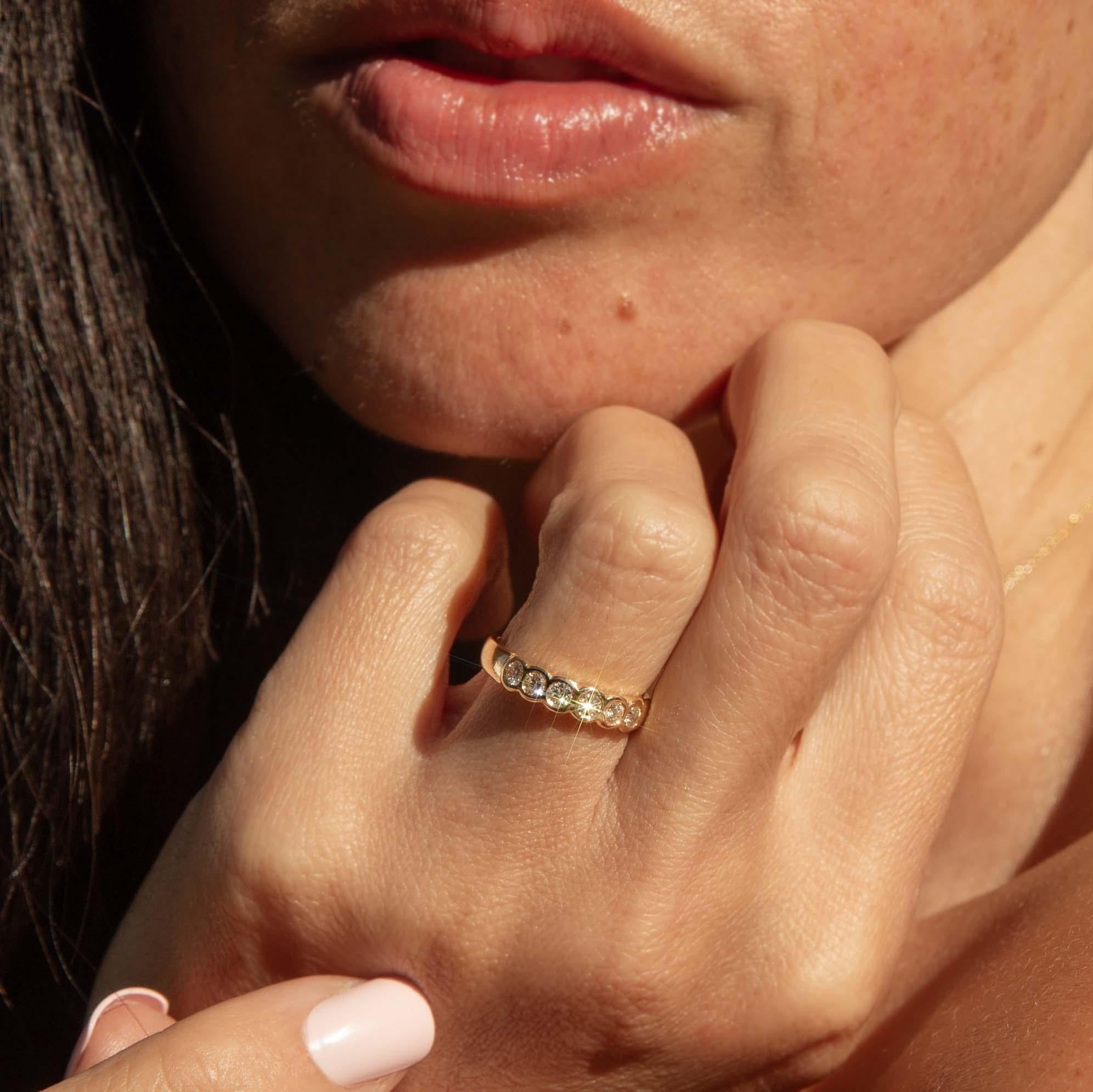 Erhöhen Sie Ihre Eleganz mit dem Adelyn 1970er Diamantring mit fünf Steinen, der aus glänzendem 18 Karat Gold gefertigt ist. Jeder Diamant funkelt mit einer romantischen Geschichte und harmoniert perfekt in einem zeitlosen Tanz des Lichts. Dieses
