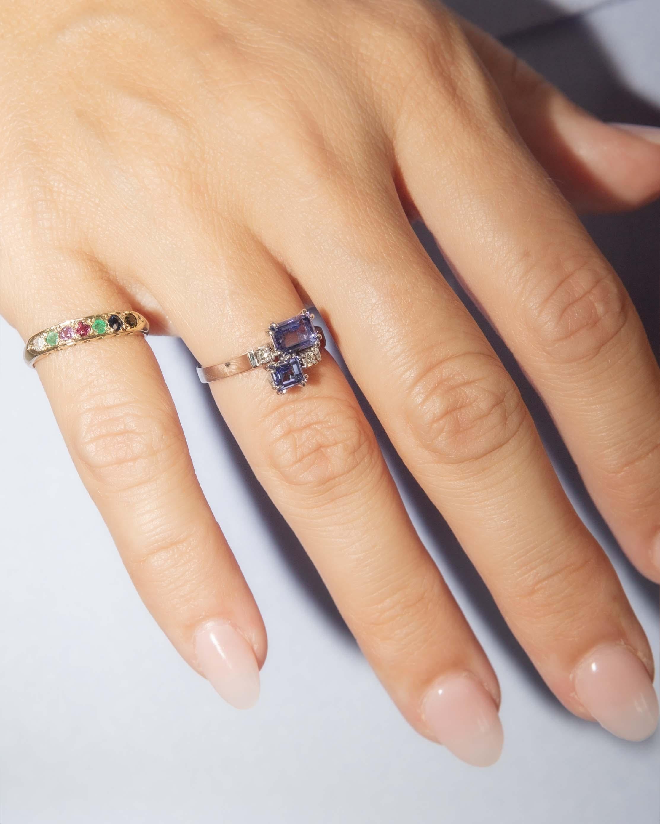 Los susurros del crepúsculo danzan sobre el Anillo de Diamantes Gemelos Lilly de Tanzanita, donde las gemas violetas irradian como estrellas atrapadas en un abrazo celestial. Engarzado en oro blanco de 18 quilates, cada destello de luz teje una