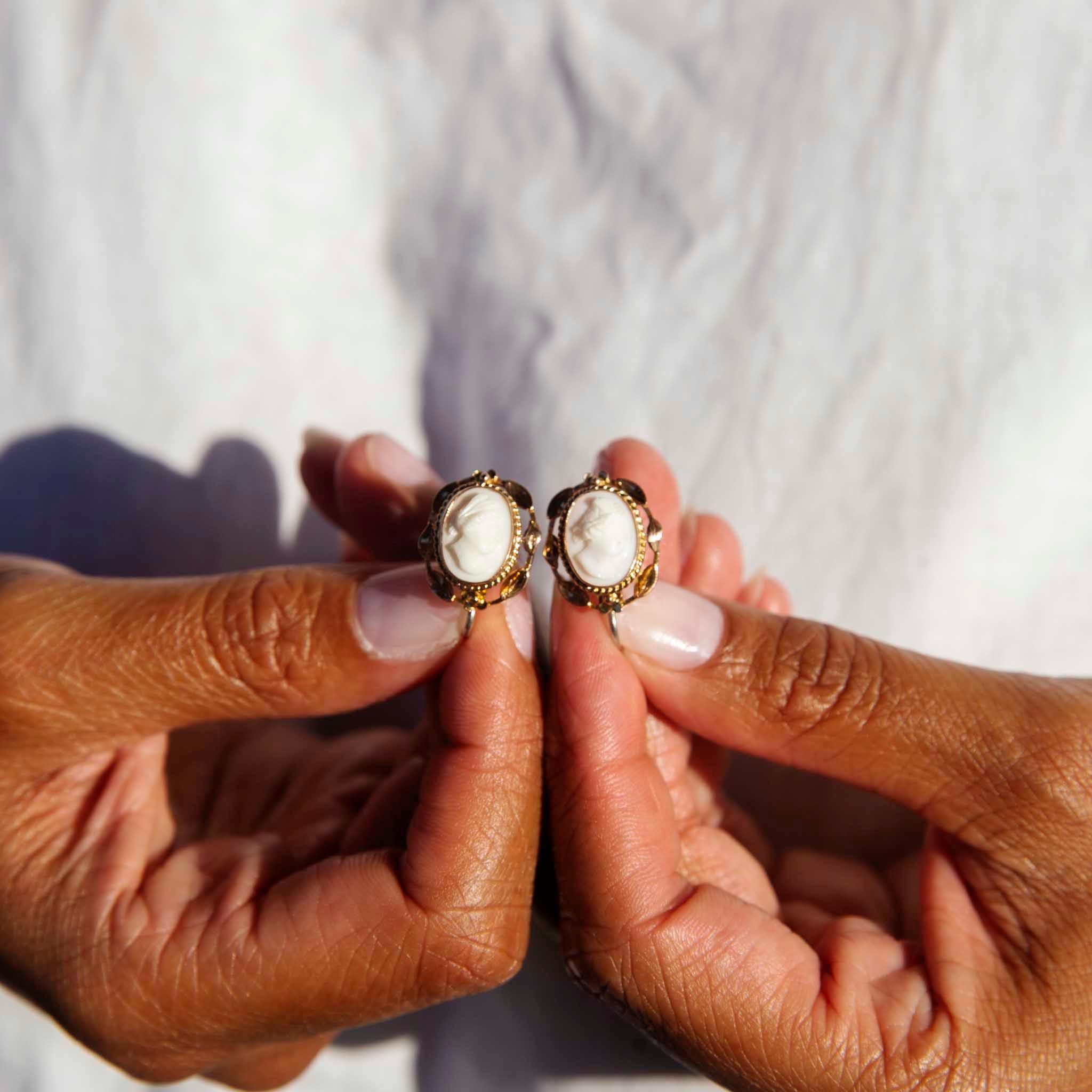 Carefully crafted in 9 carat yellow gold, these darling antique-inspired vintage earrings each hold a white shell cameo of a lady in an ornate leaf-like frame with a milgrain border. These lovely adornments have been named The Beatrice Earrings.