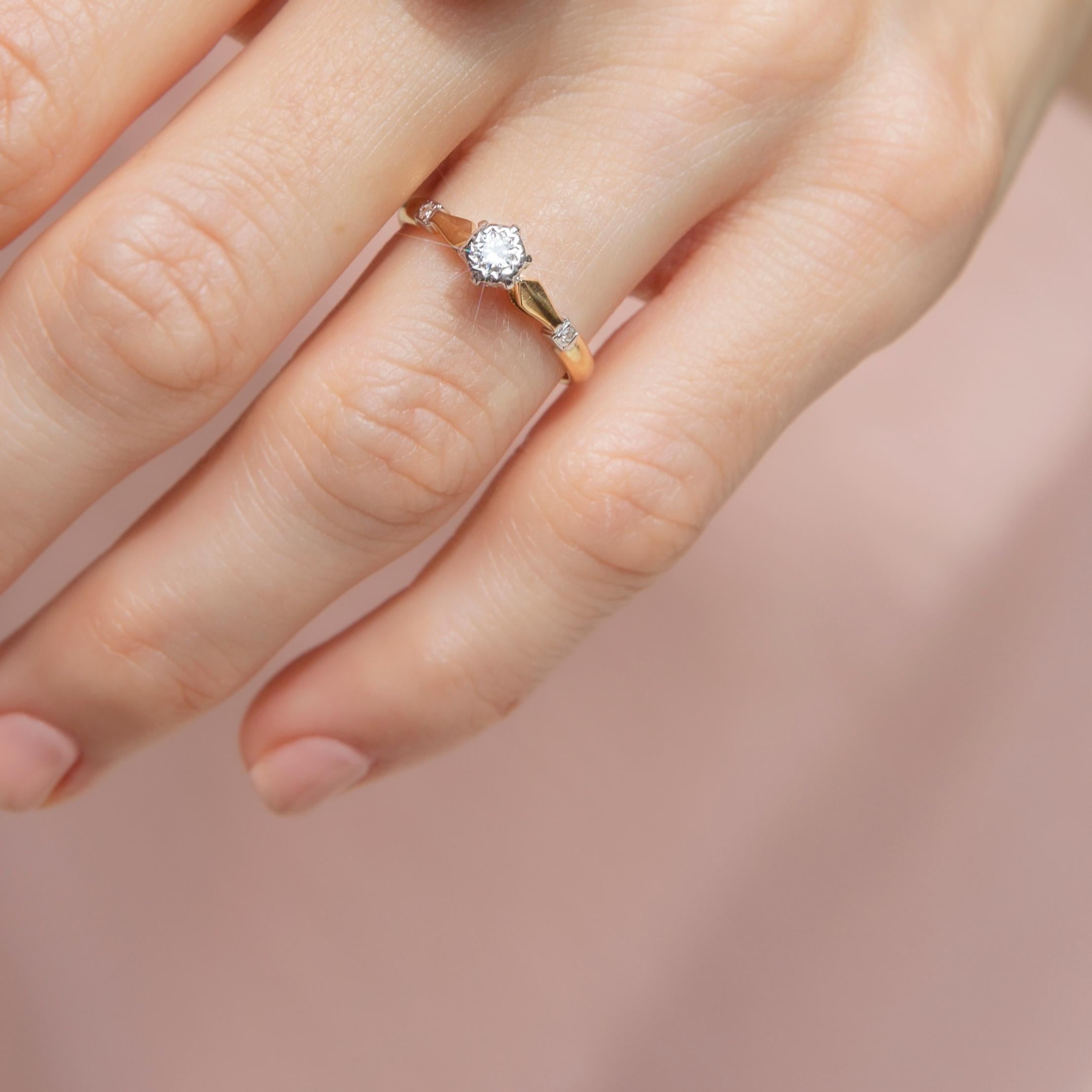 Thoughtfully crafted in 18 carat gold, this ever-so-lovely vintage 1980s ring features a shimmering round brilliant cut diamond in a white gold setting and is flanked by a duo of smaller diamonds on a yellow gold band. The Shirley Ring has a quiet